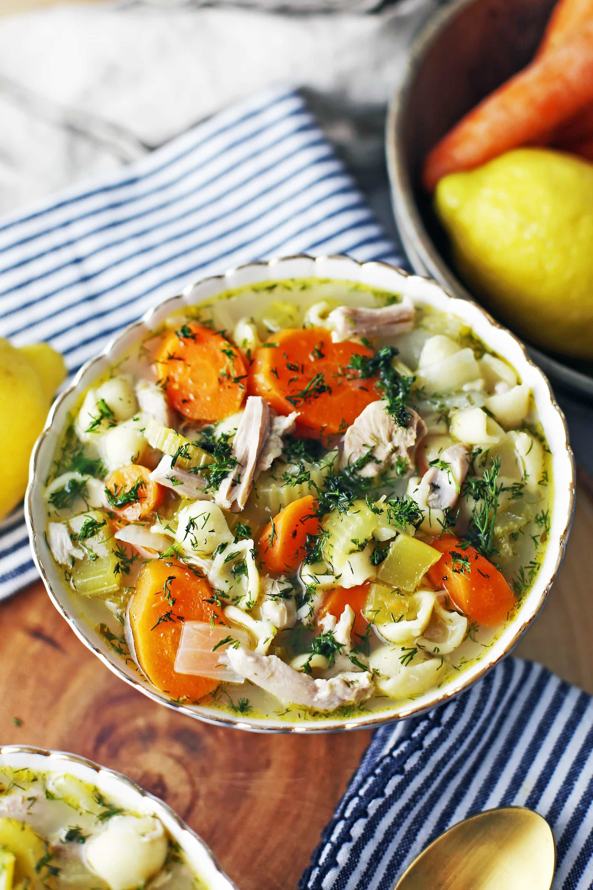 A full bowl of Instant Pot Lemon Dill Chicken Noodle Soup with carrots, celery, and onions.