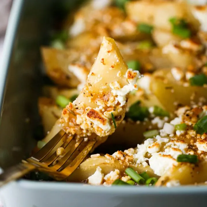 A close-up of a lemon feta potato wedge pieced on a fork.