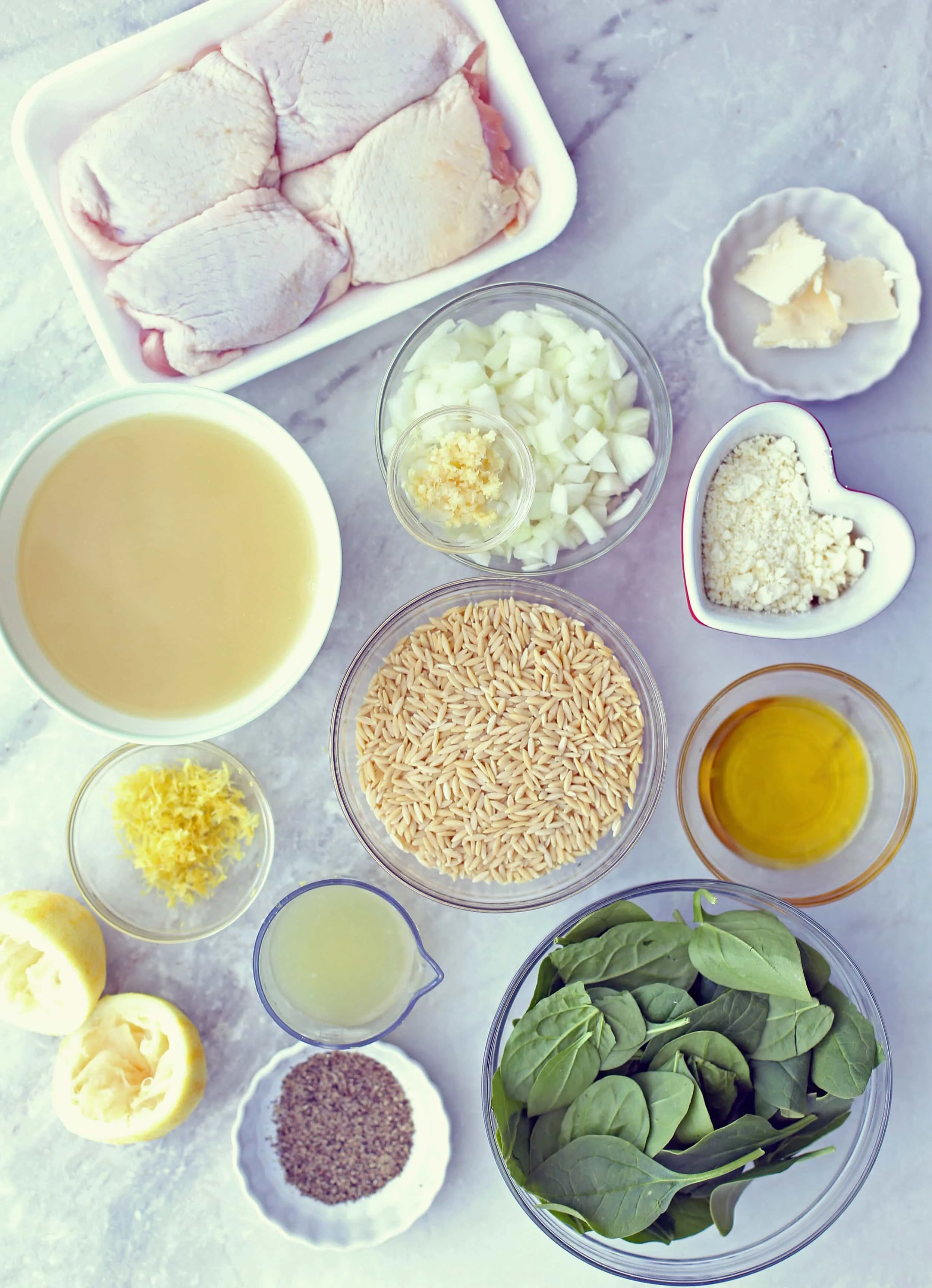 Pack of chicken thighs, bowls of orzo, spinach, feta, onions, garlic, lemon juice, zest, black pepper, and chicken broth.