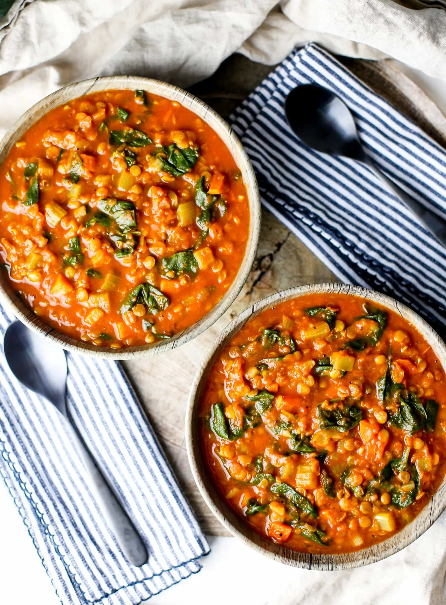 Overhead shot of two bowls of spiced Instant Pot Lentil Soup with two black spoons on the side.