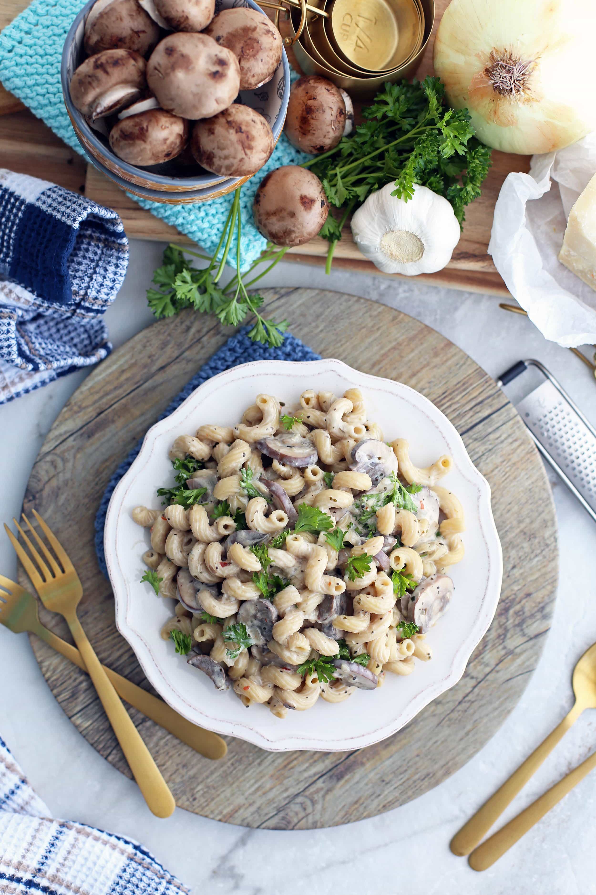 Overhead view of a white bowl containing mushroom pasta with creamy parmesan sauce.