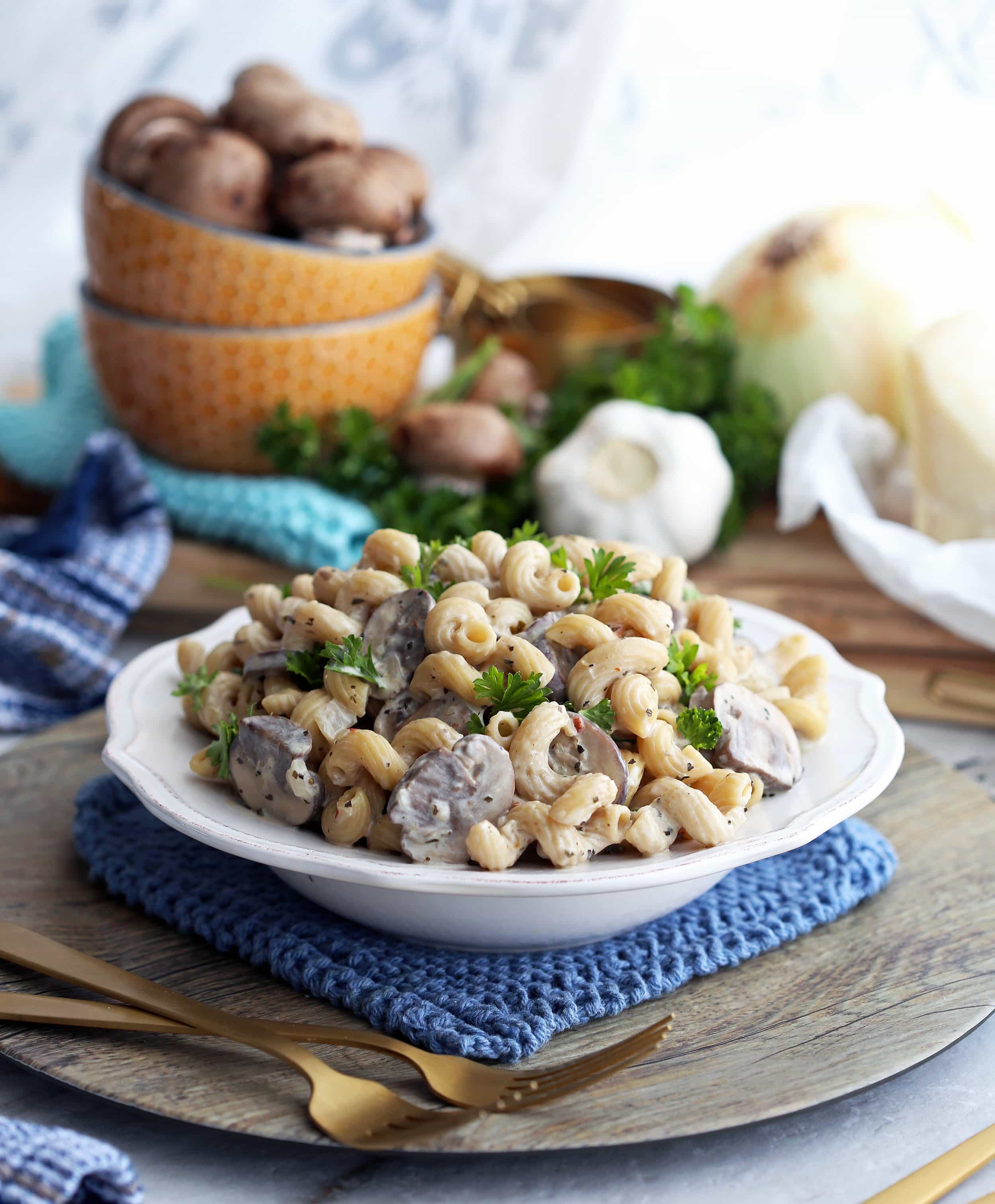 Cavatappi pasta and cremini mushrooms in a creamy parmesan sauce that's garnished with fresh parsley in a white pasta bowl.