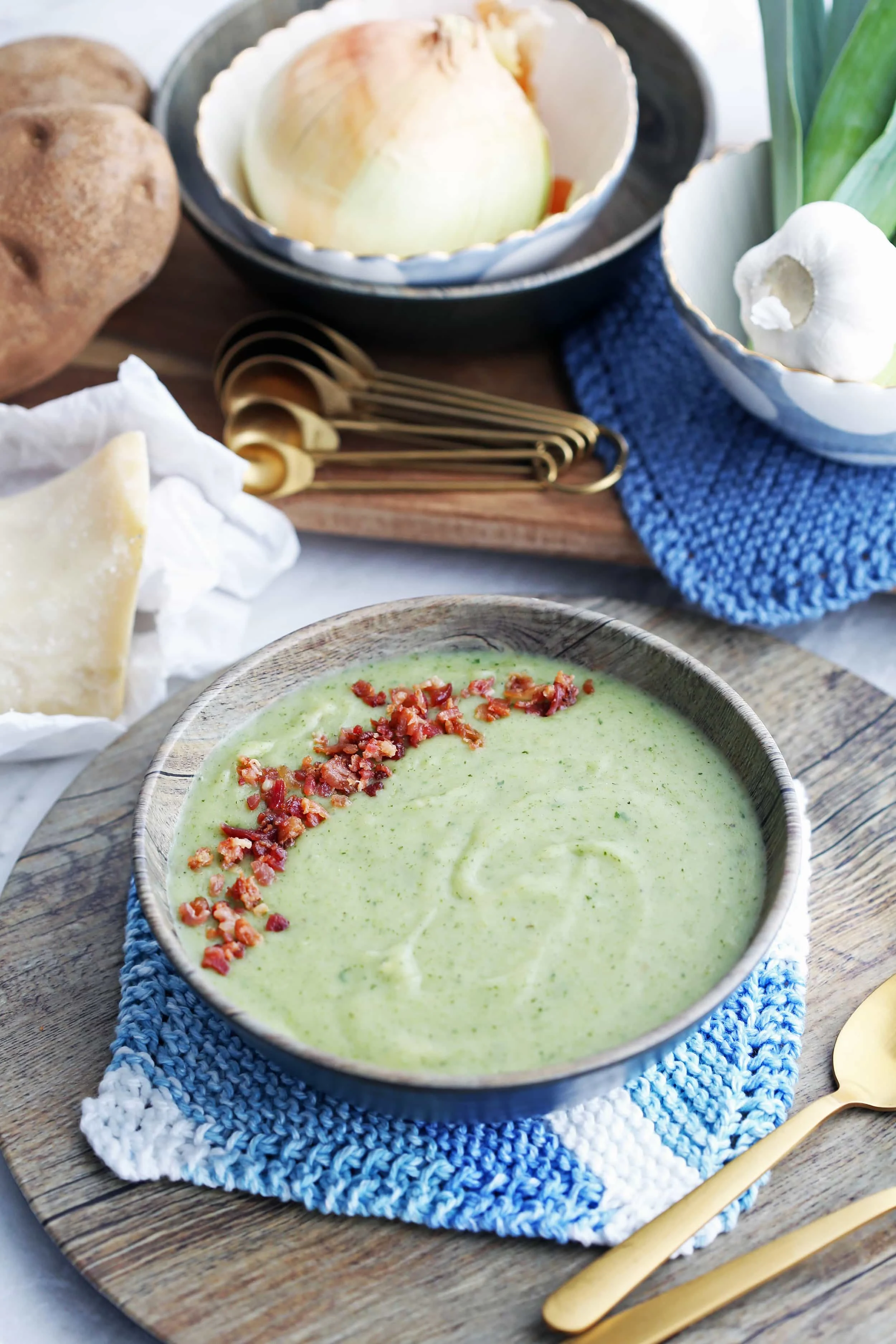 Creamy Potato Leek Soup with Spinach and Parmesan that's topped with bacon bits in a wooden bowl.