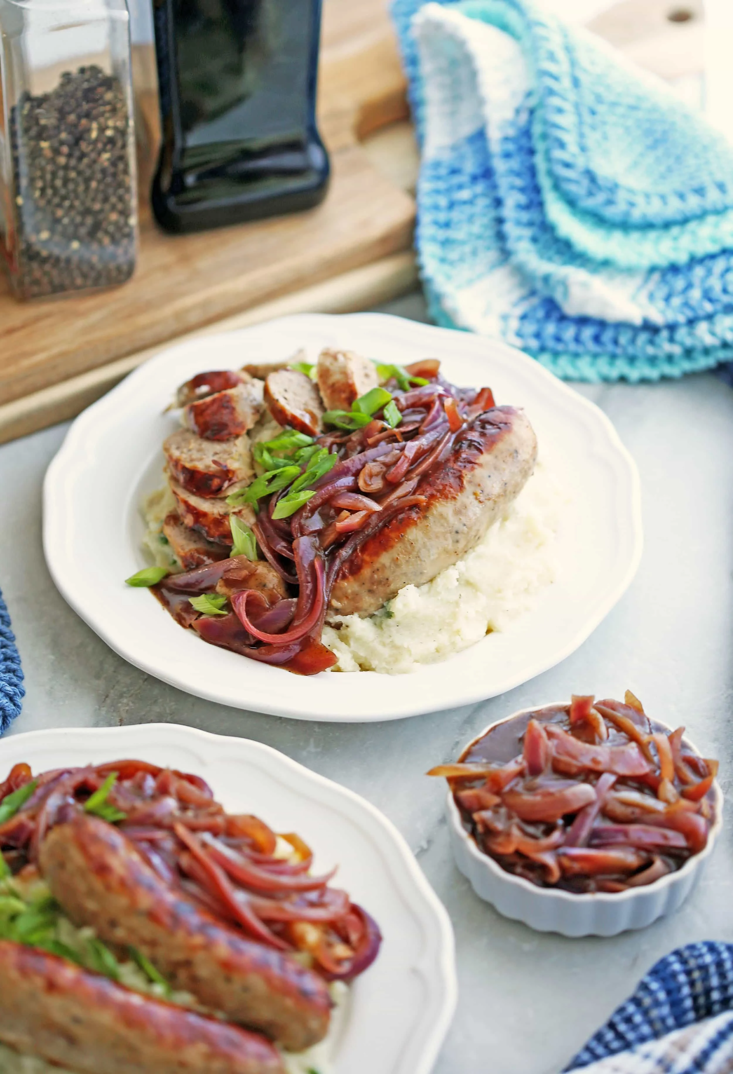 Two plates of Instant Pot Bangers and Mash with Onion Gravy with more gravy in a small white bowl to the side.