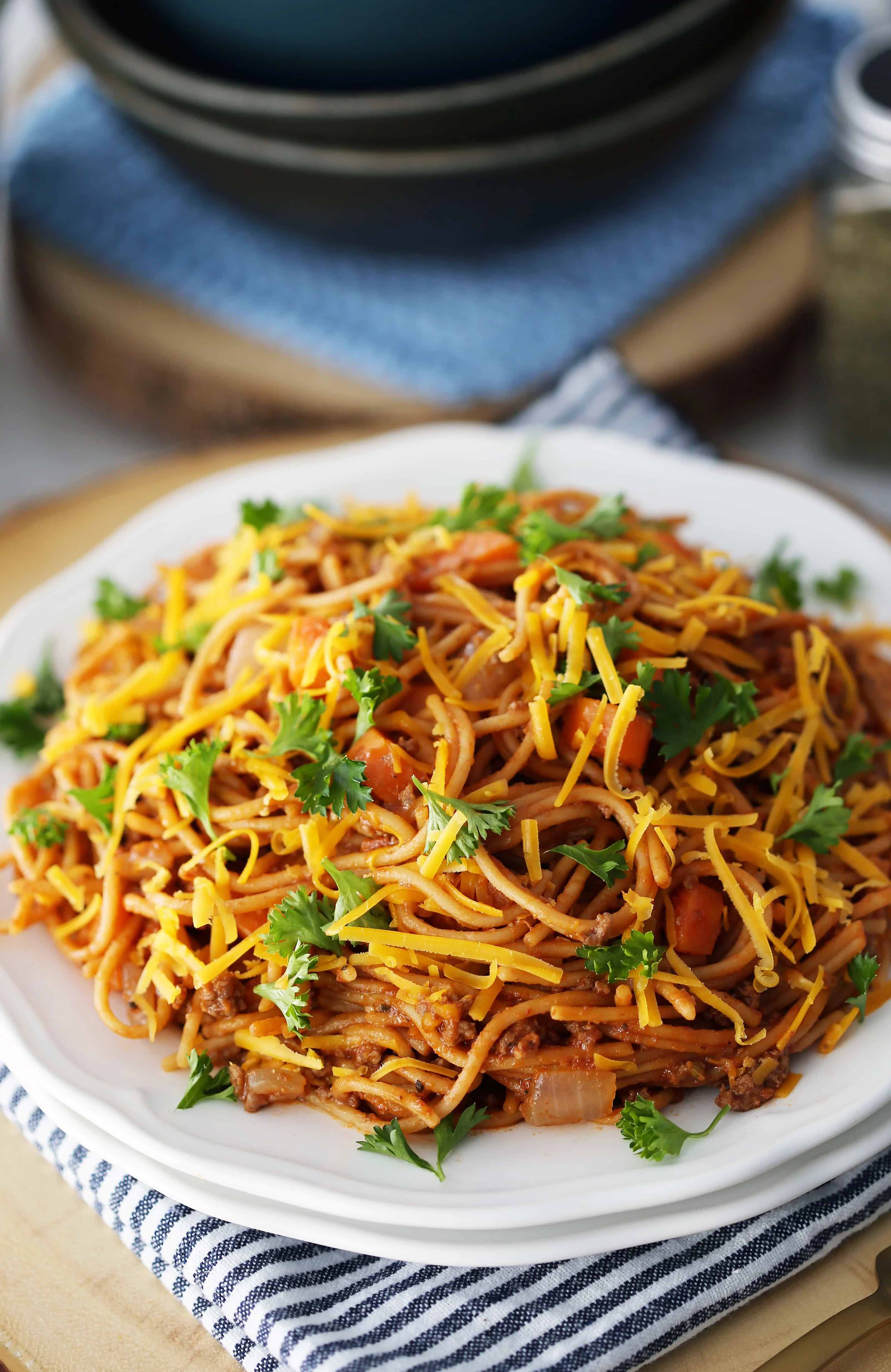 Instant Pot Spaghetti with Meat Sauce on a white plate topped with cheese and parsley.