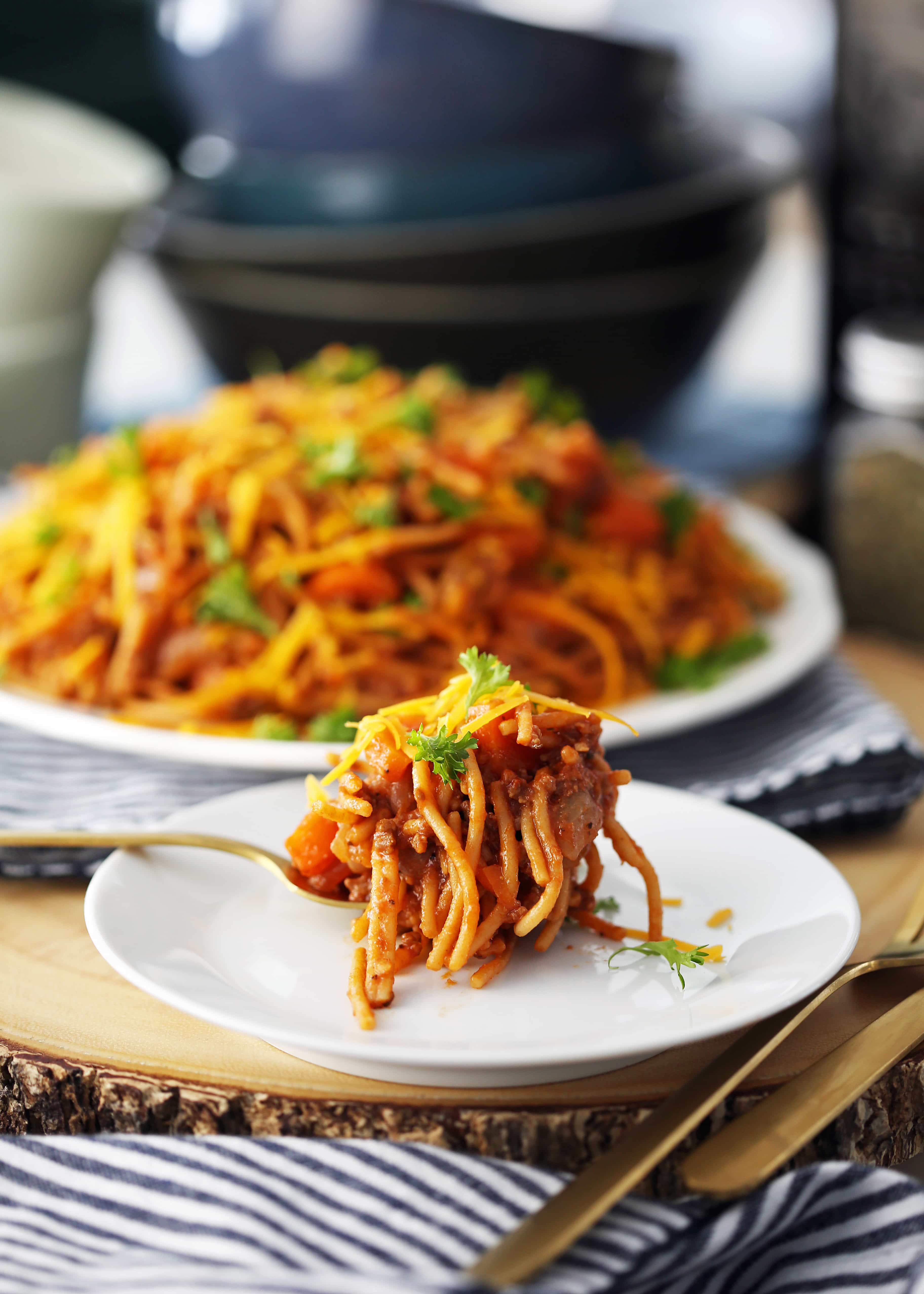 Instant Pot Spaghetti and Meat Sauce on a white plate with a fork holding the pasta on top of another white plate.