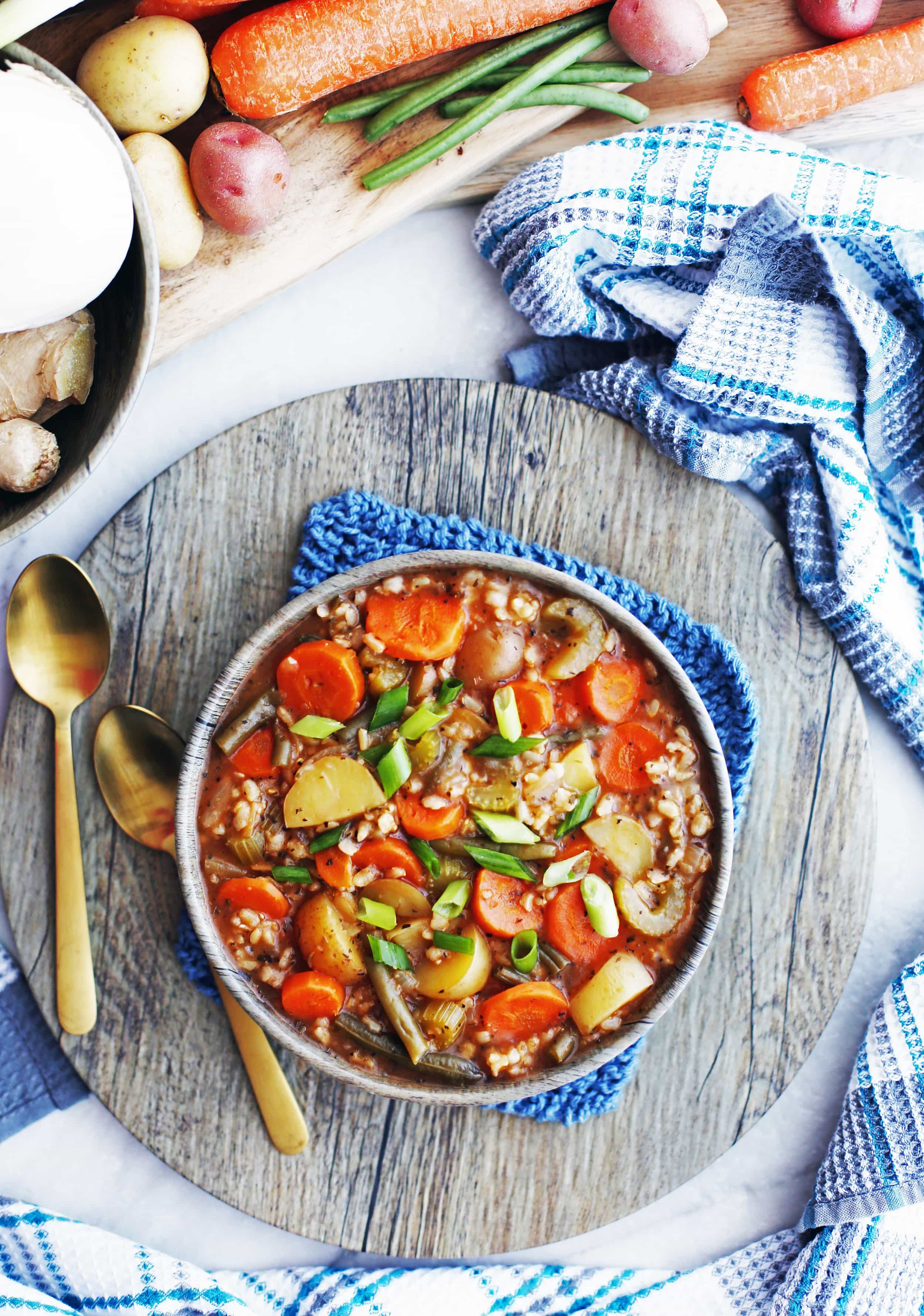 An overhead shot of a bowl of hearty vegetable and brown rice soup, which includes carrots, potatoes, and green beans.