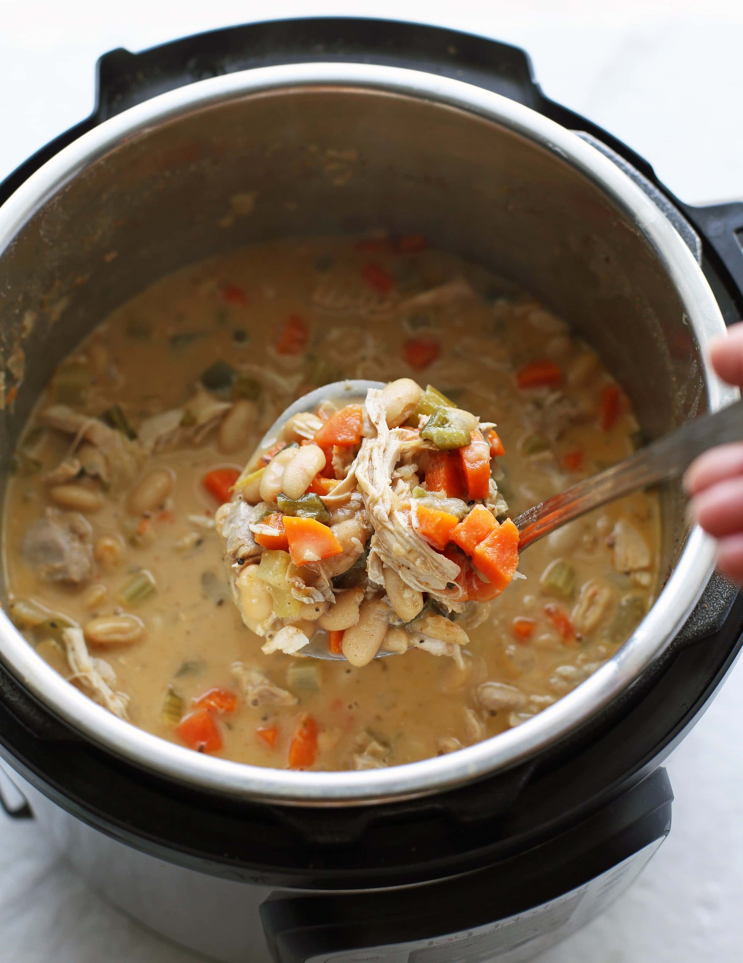 A large metal ladle holding a big scoop of Instant Pot White Bean Chicken Chili.