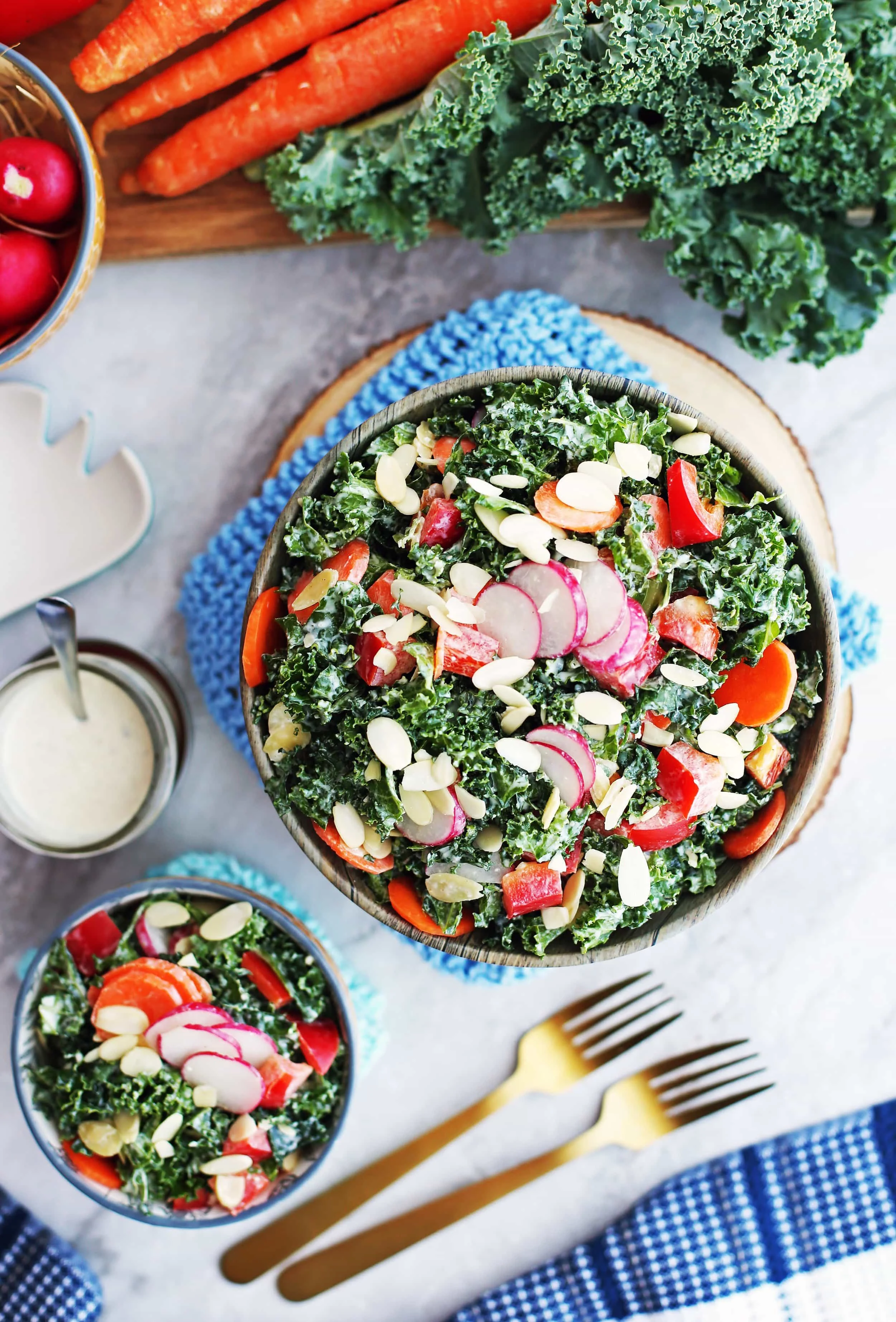 Overhead view of a big and small bowl of Crunchy Kale, Carrot, Pepper, and Radish Salad with Creamy Parmesan Yogurt Dressing.
