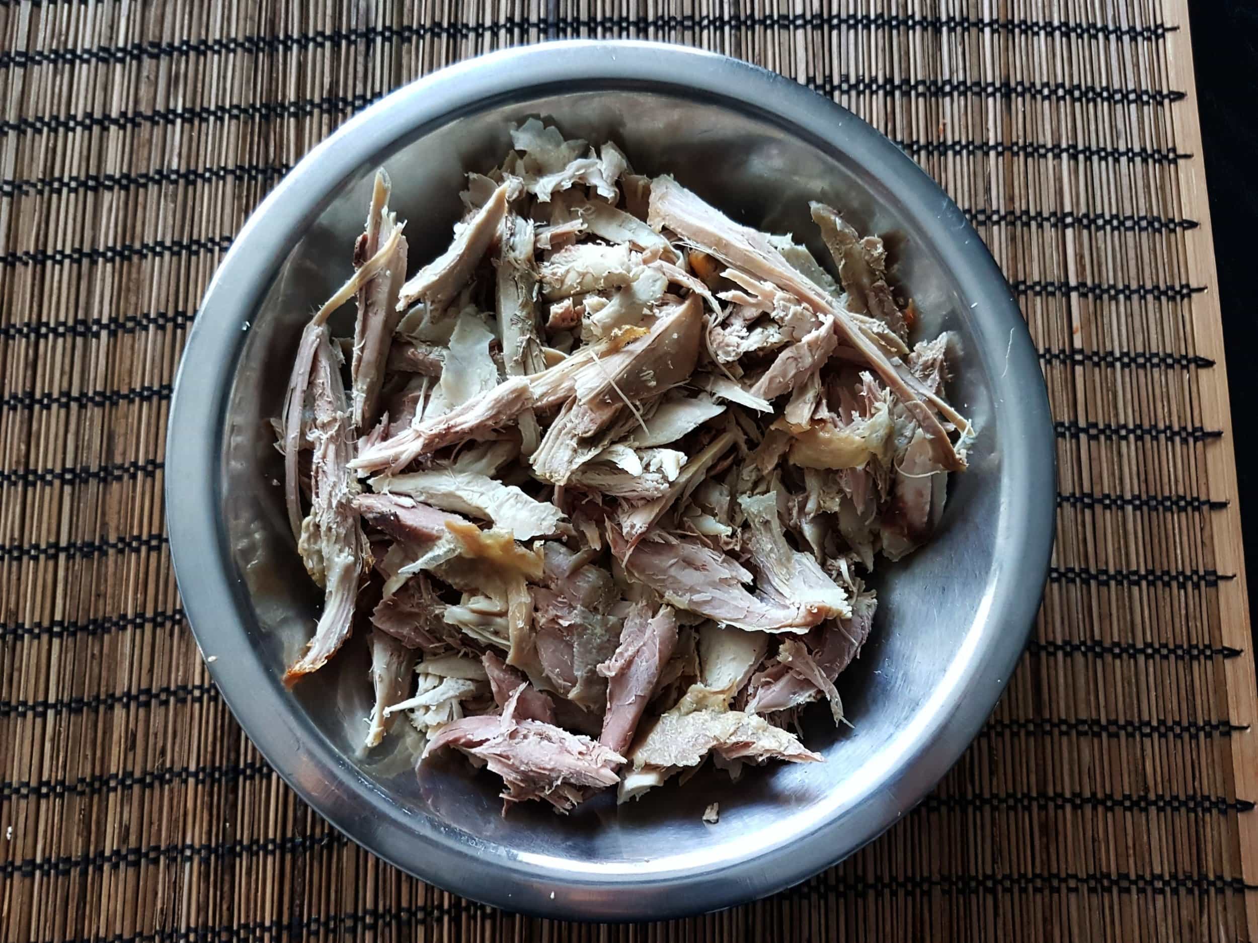 Shredded leftover turkey in a metal bowl.