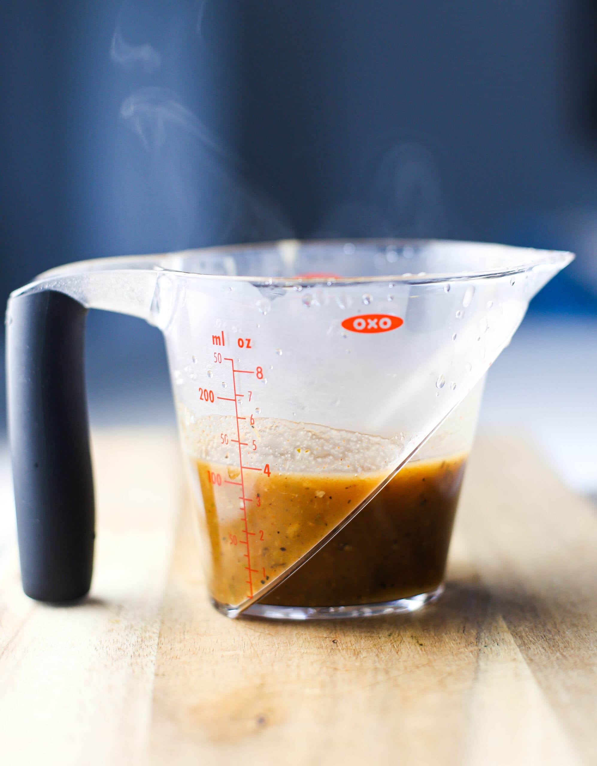 Lemony herb chicken broth sauce in a measuring cup.
