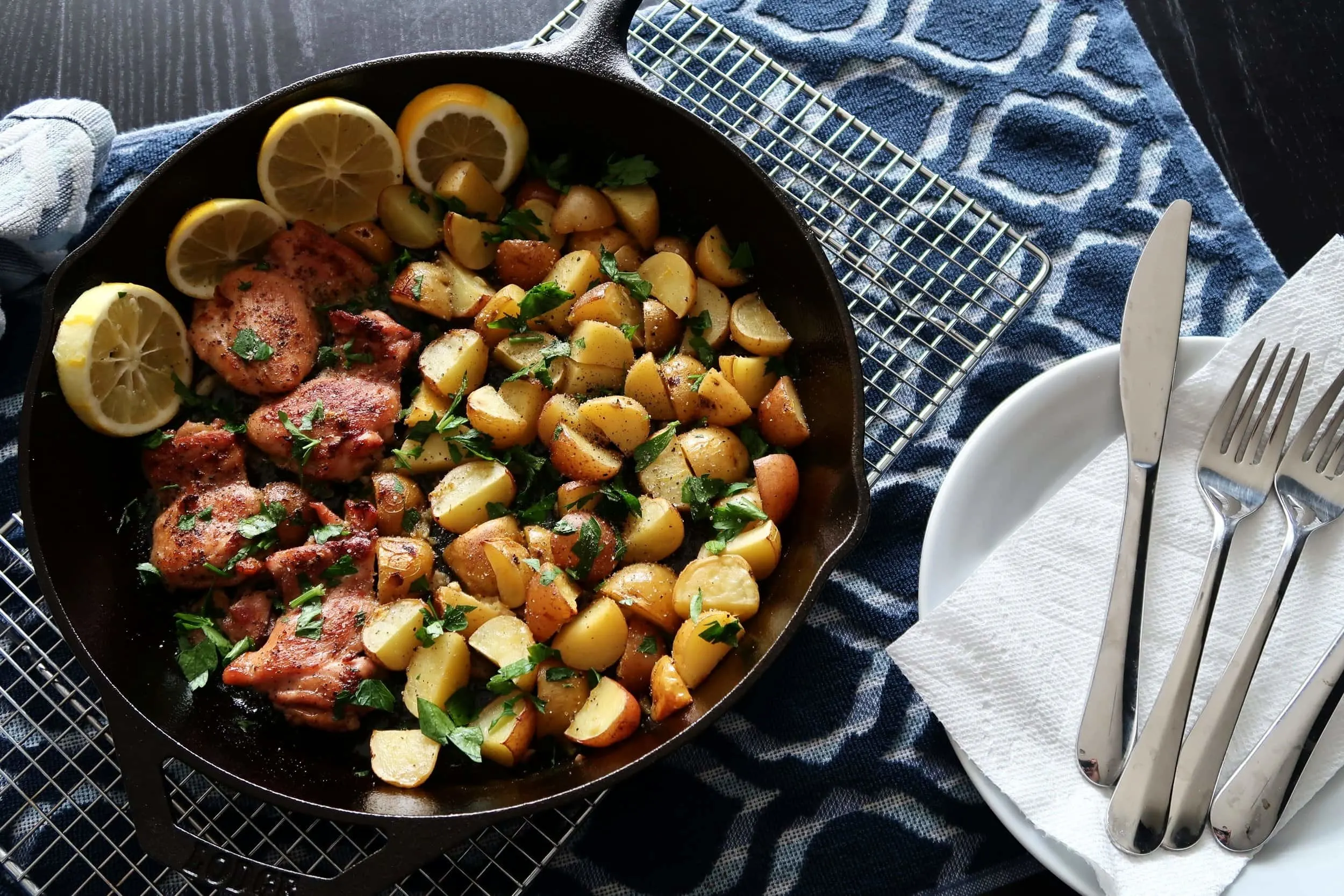 Lemon Garlic Chicken with Baby Potatoes with plates and utensils nearby.