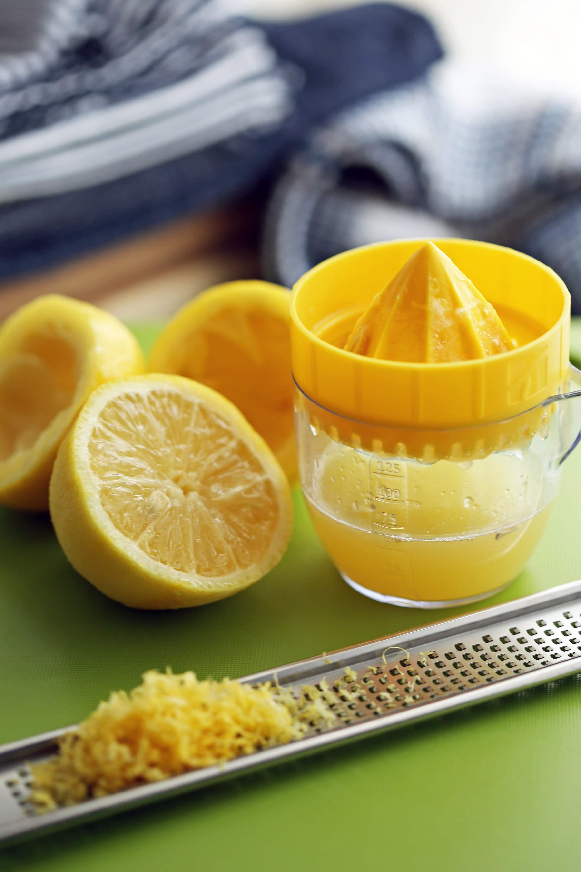 Lemon juice in a small measuring cup and lemon zest on a citrus zester.