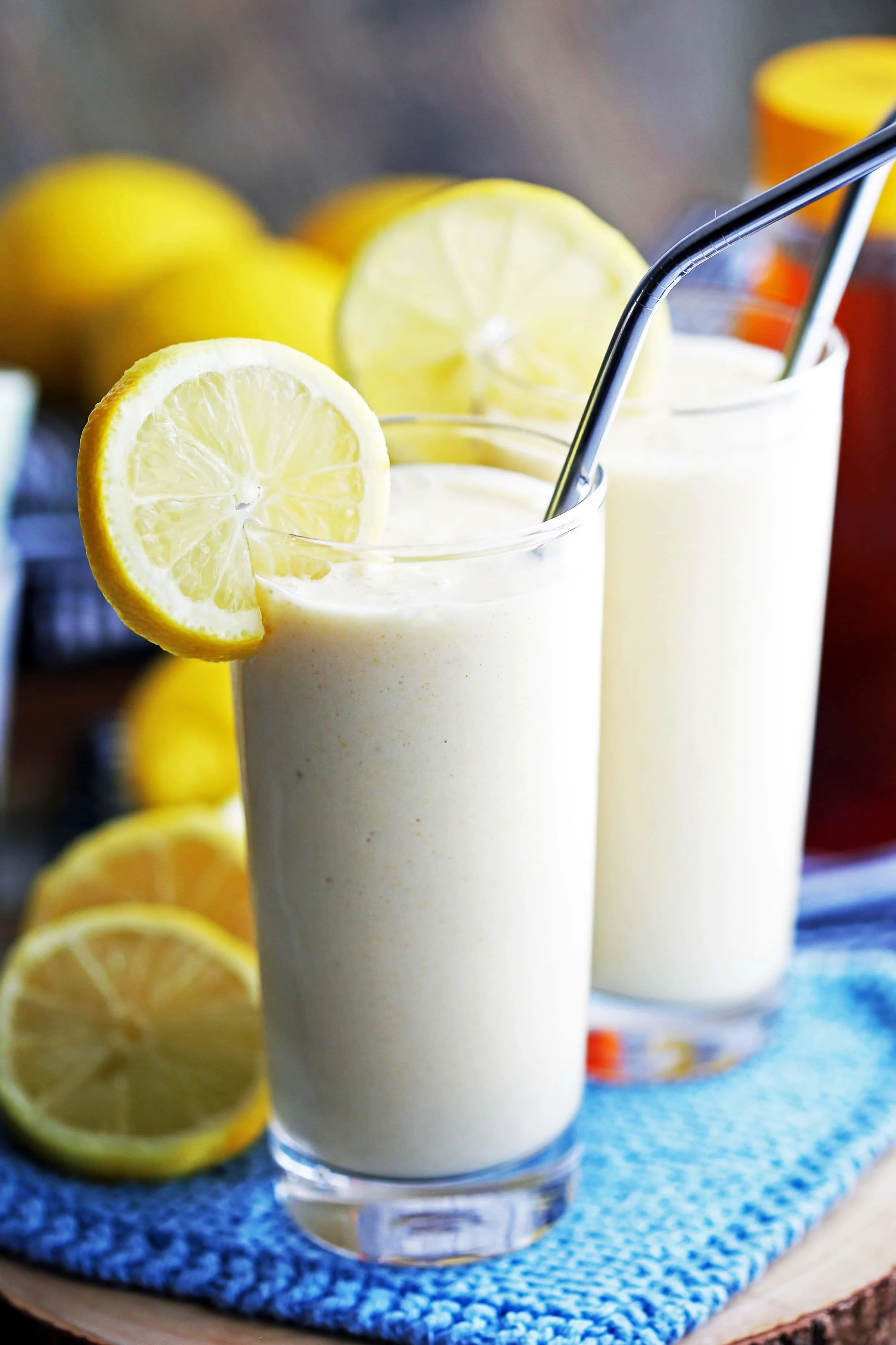 Lemon Pineapple Smoothie drinks in tall glasses with metal straws and lemon slices on the rim.