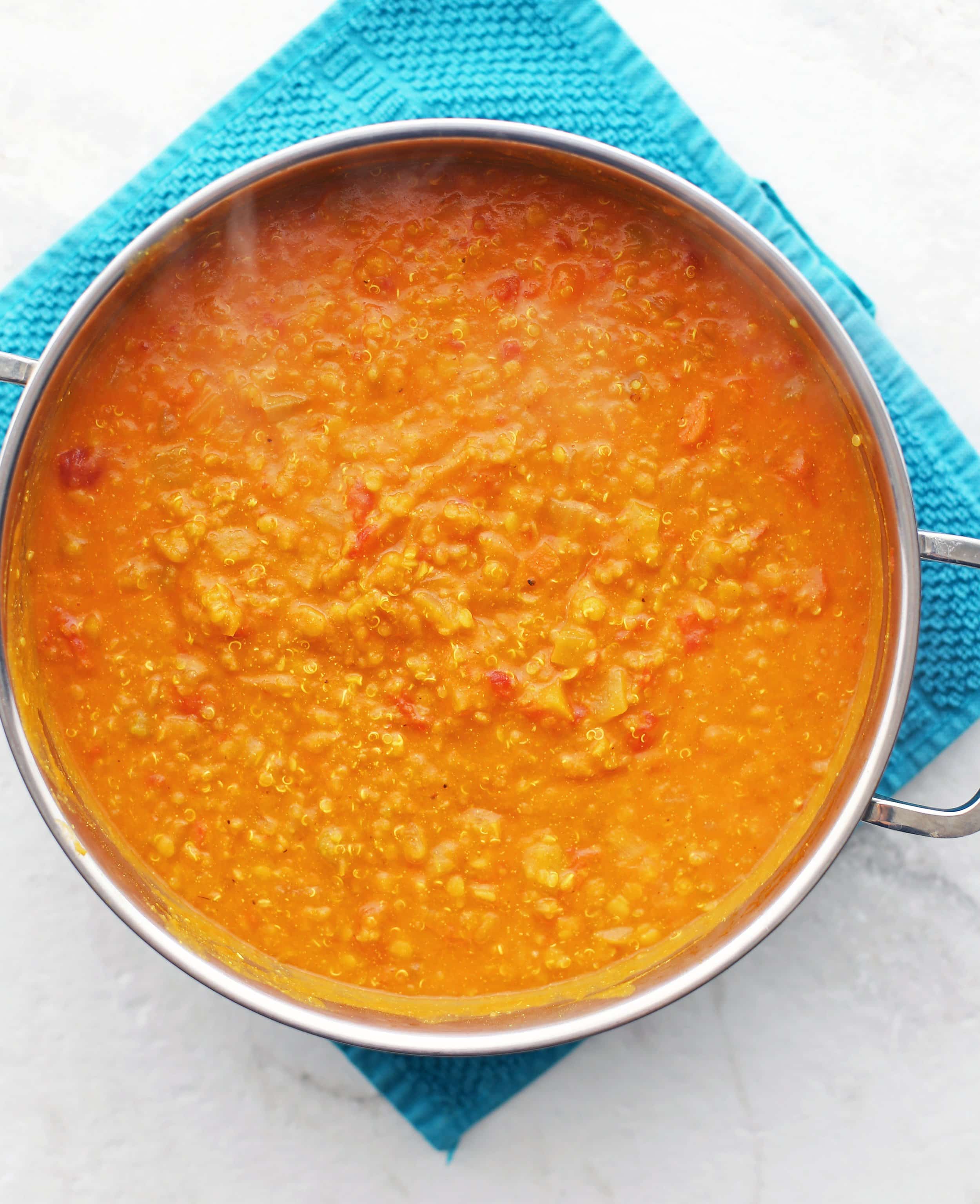 A pot of hearty Curried Red Lentil and Quinoa Vegetable Soup in a large metal pot.