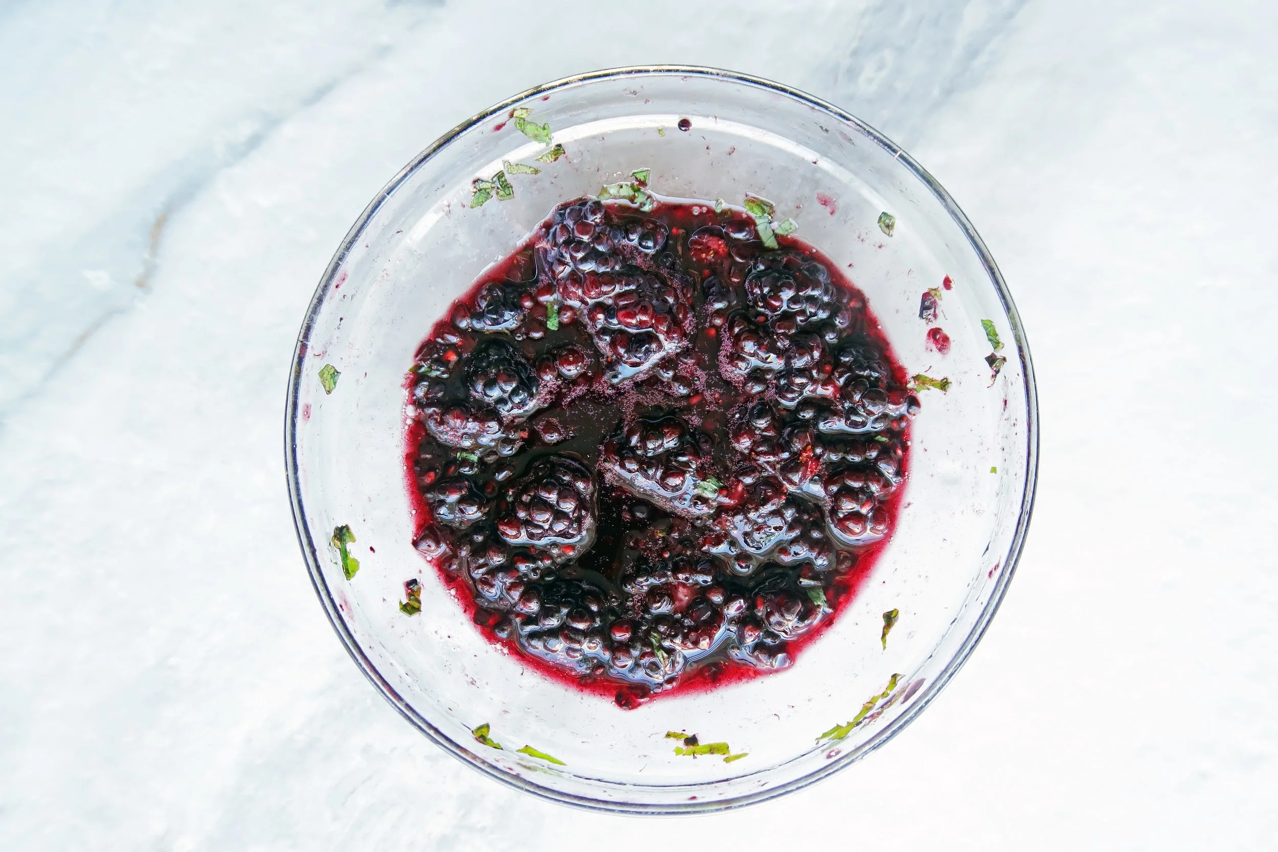 Macerated blackberries and mint in a bowl.
