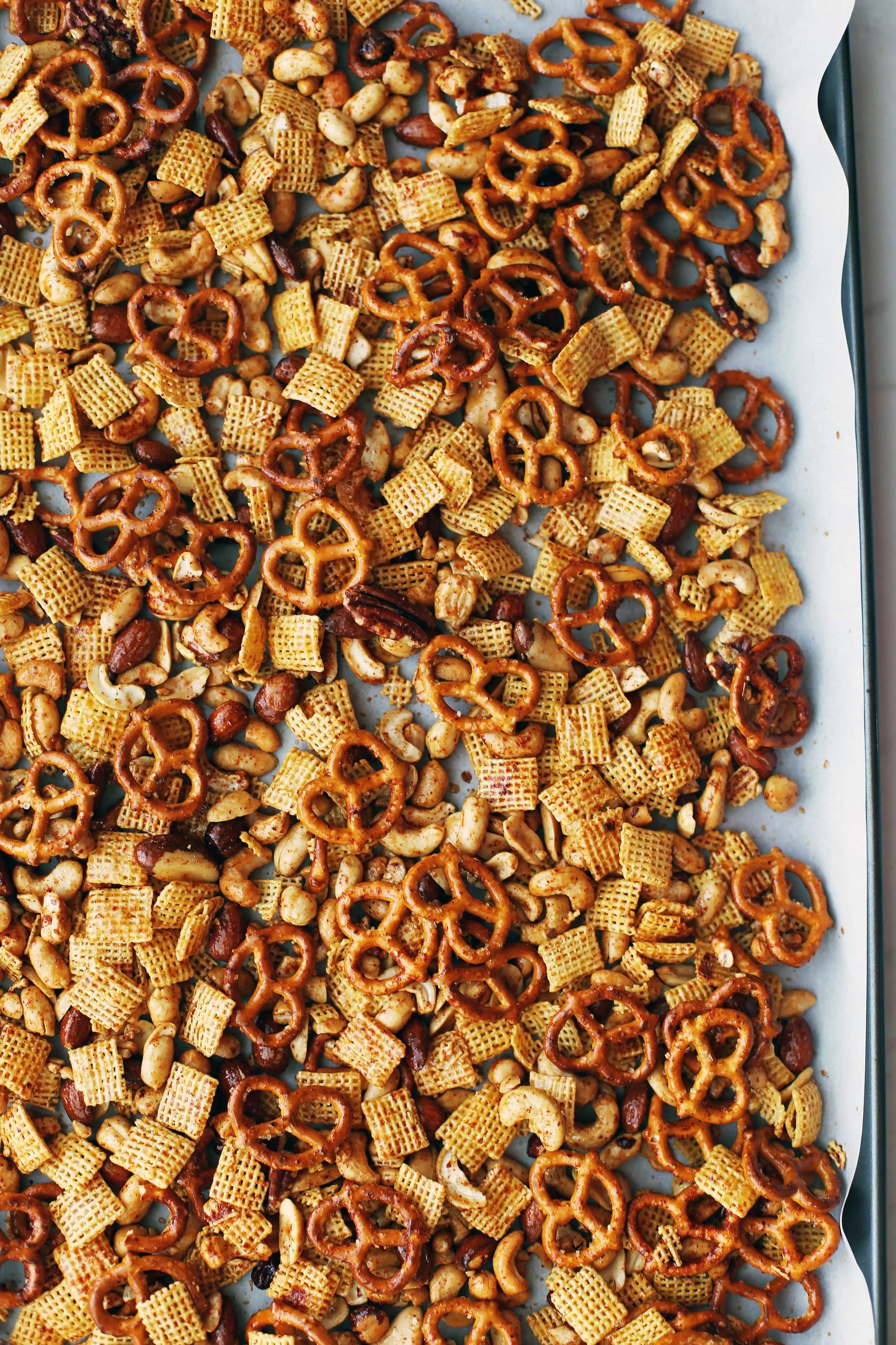 Baked Maple Chili Nuts and Chex Snack Mix on a parchment paper lined baking sheet.