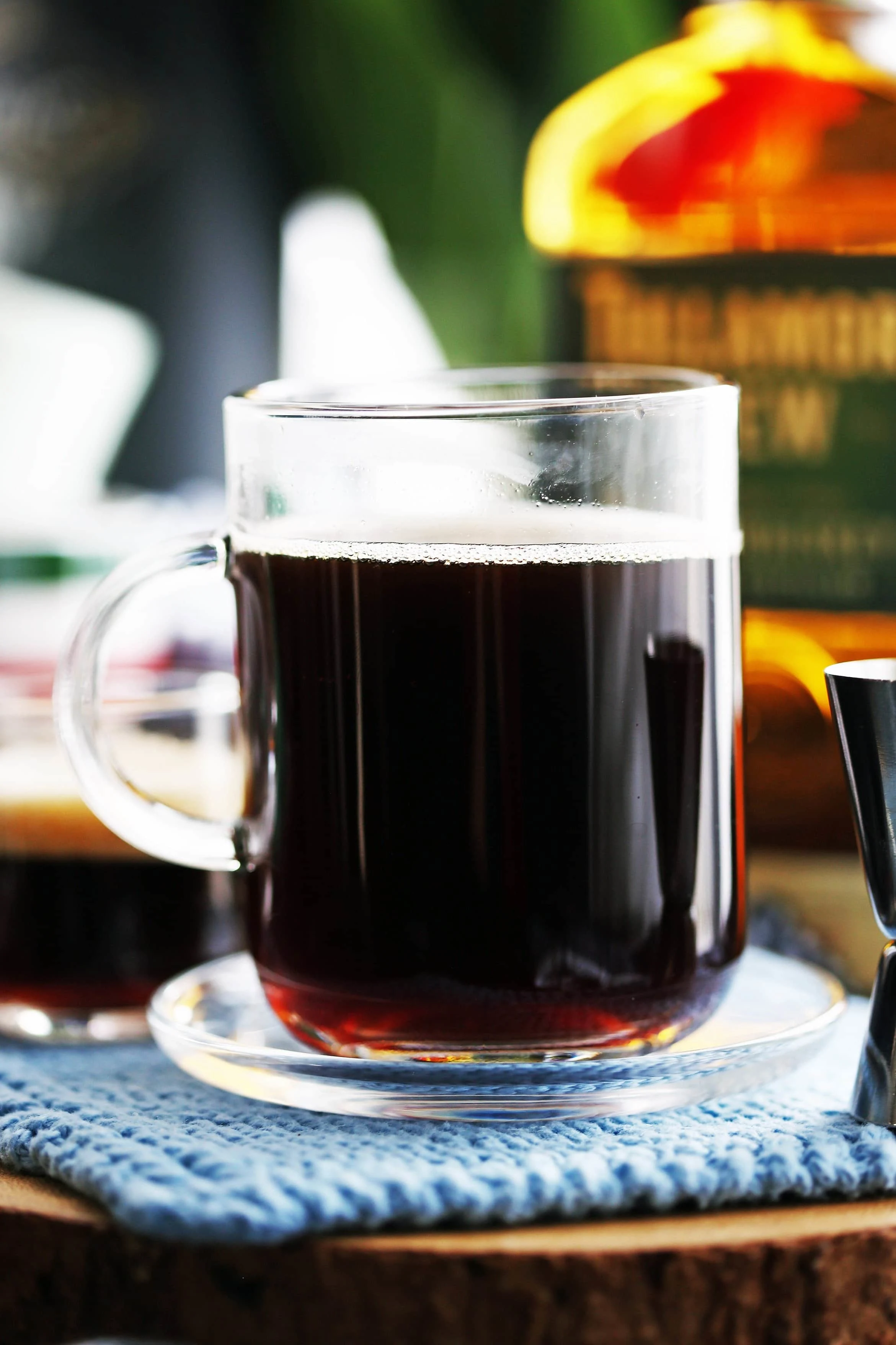 A side view of a glass mug filled with coffee and a small amount of maple syrup and Irish whiskey.