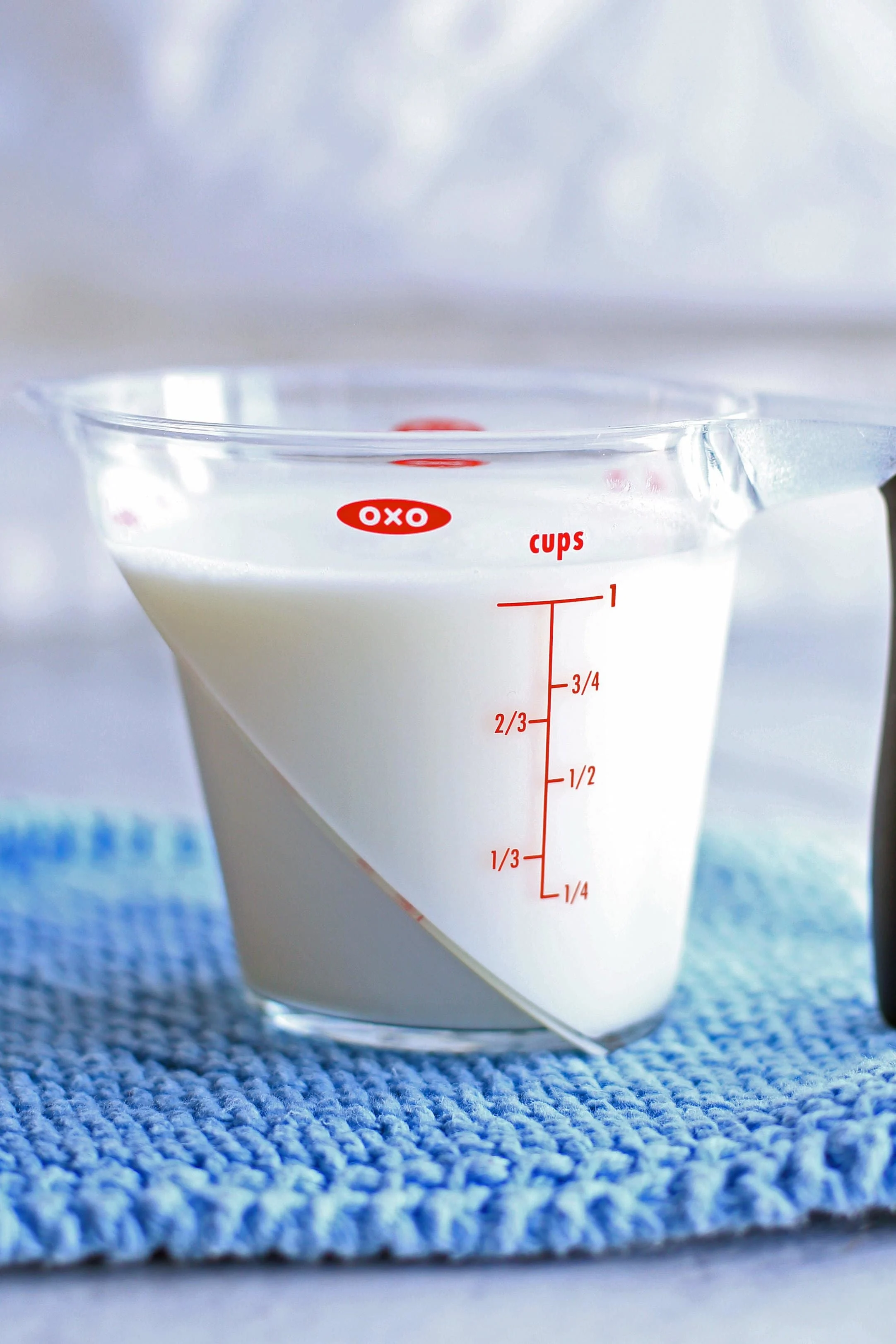 A liquid measuring cup containing a cup of milk and one tablespoon of white vinegar.