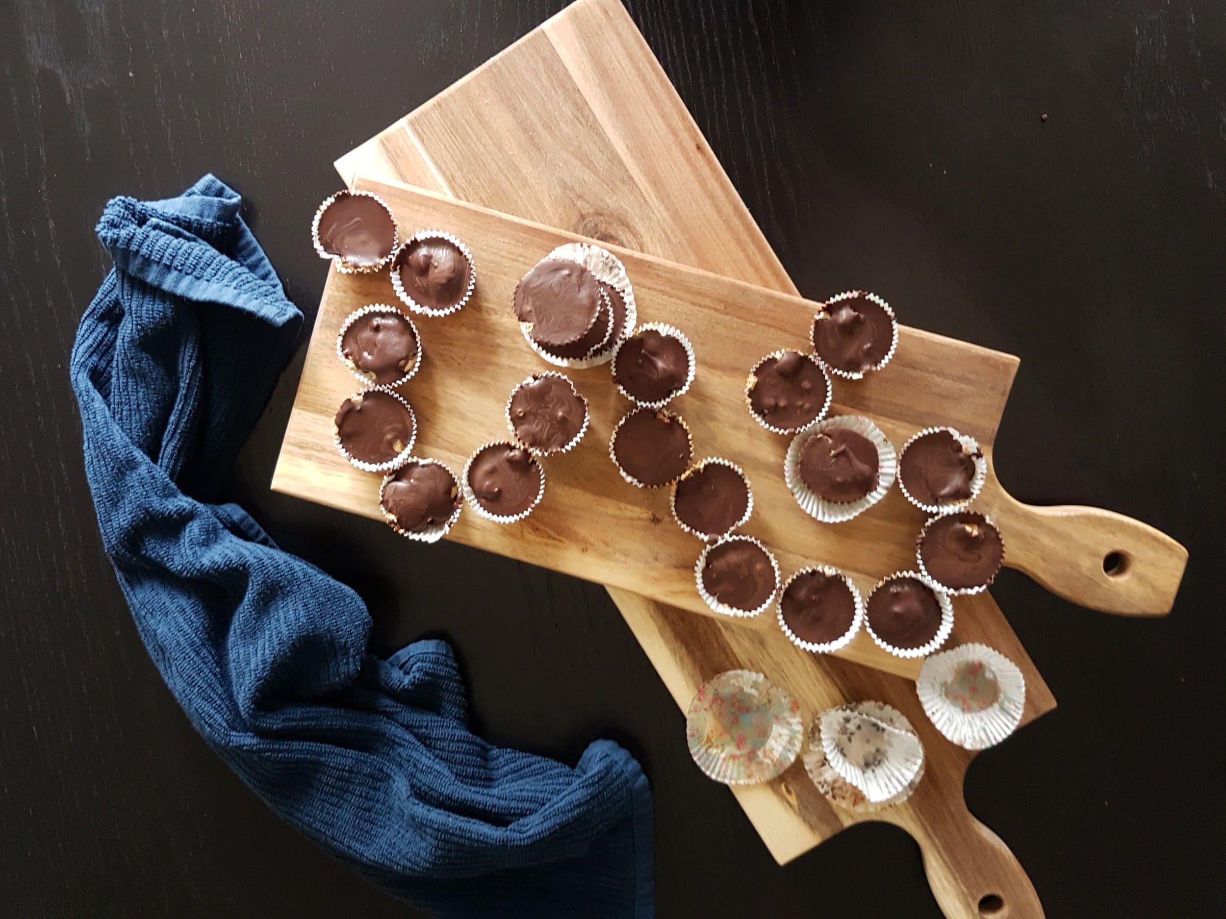 Mini Chocolate Cups with Pumpkin Spice Whipped Cream laid out on a wooden board.
