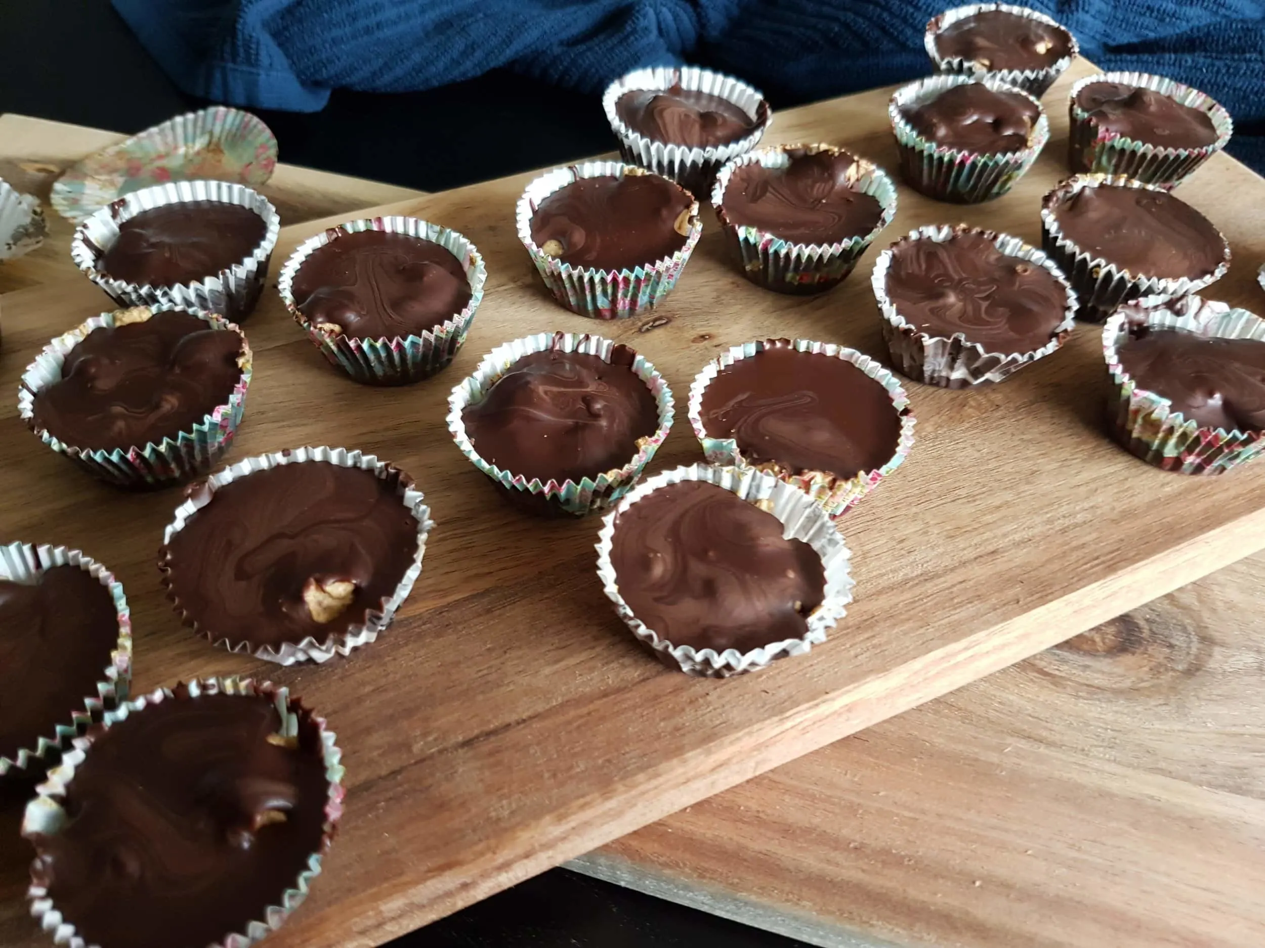 A wooden serving board of Mini Chocolate Cups with Pumpkin Spice Whipped Cream.