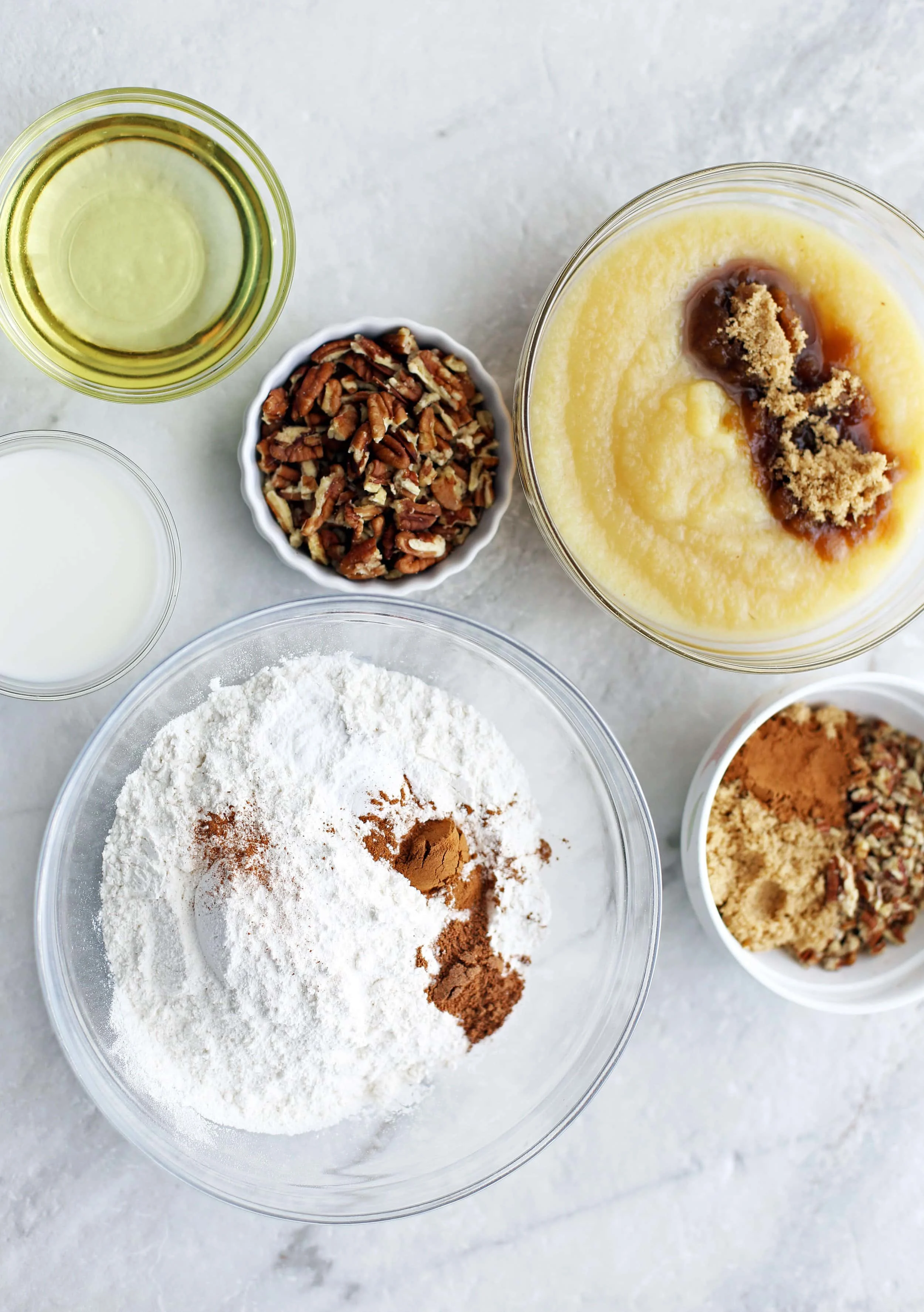 Bowls of applesauce, sugar, spices, pecans, milk, and baking soda.