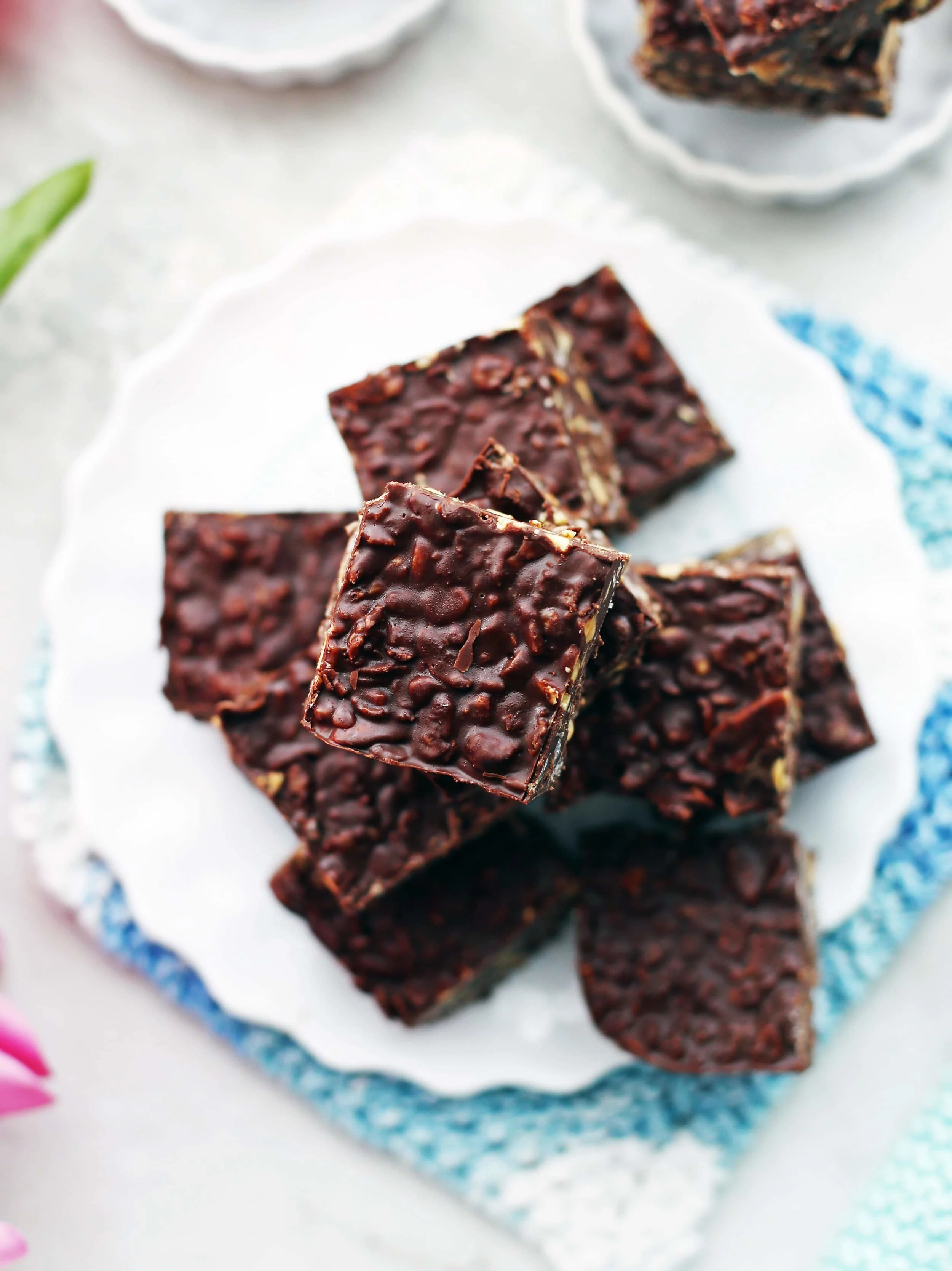 Overhead view of No-Bake Peanut Butter Chocolate Crunch Bars stacked randomly on a white plate.