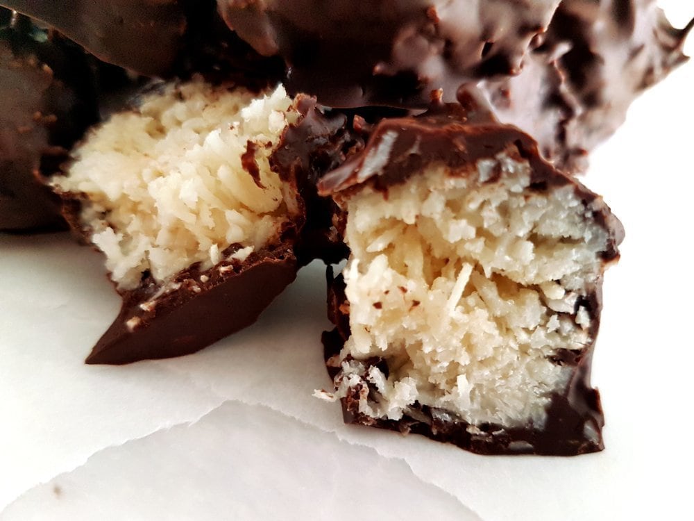 A chocolate ball cut in half showing the shredded coconut interior.