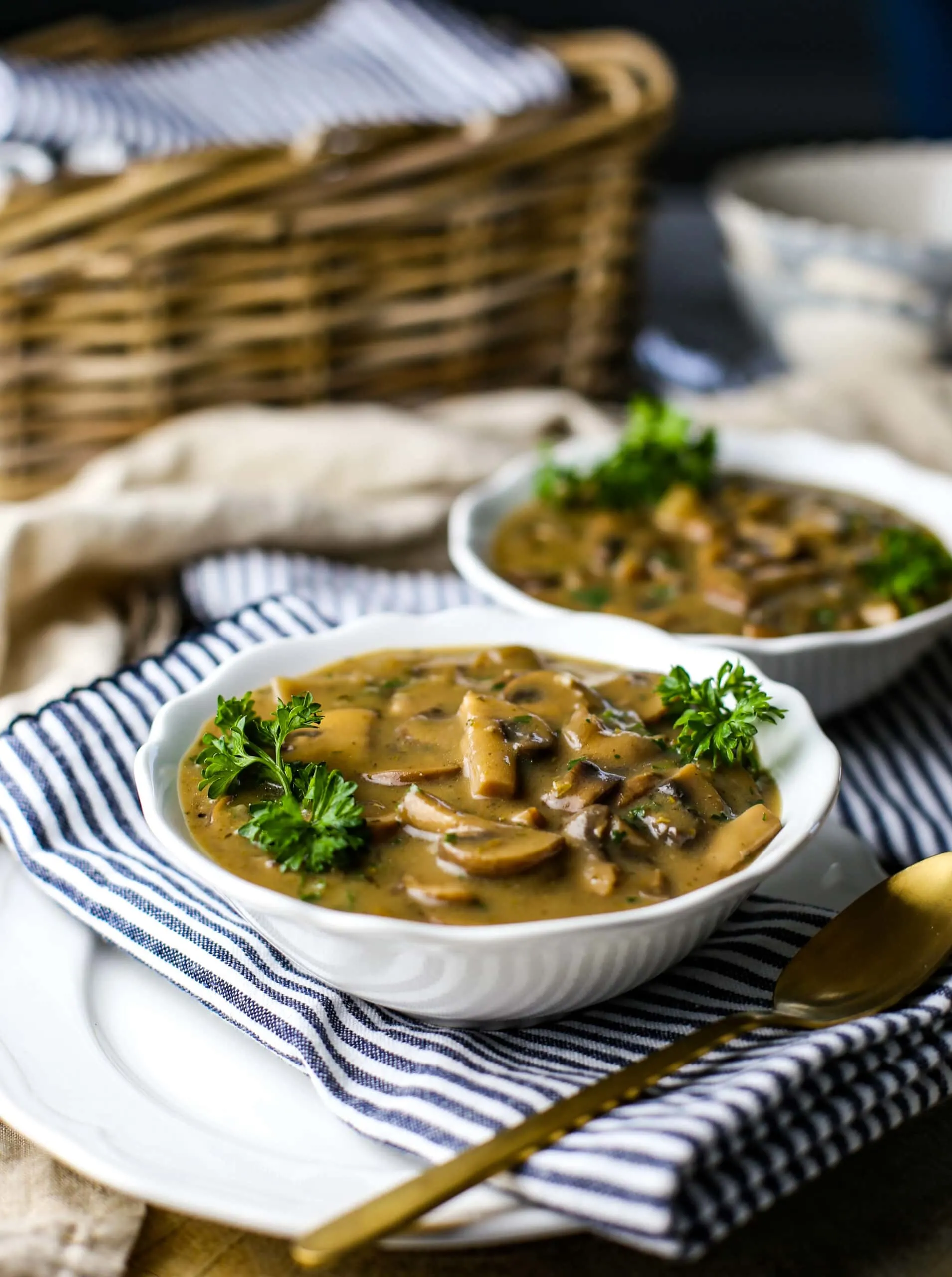 A side view of creamy vegan mushroom soup in two white bowls.