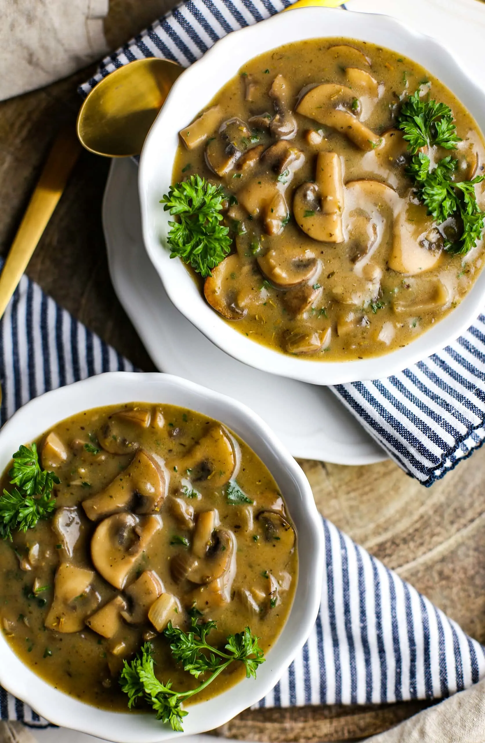 Overhead view of two bowls full of creamy vegan mushroom soup with fresh parsley.