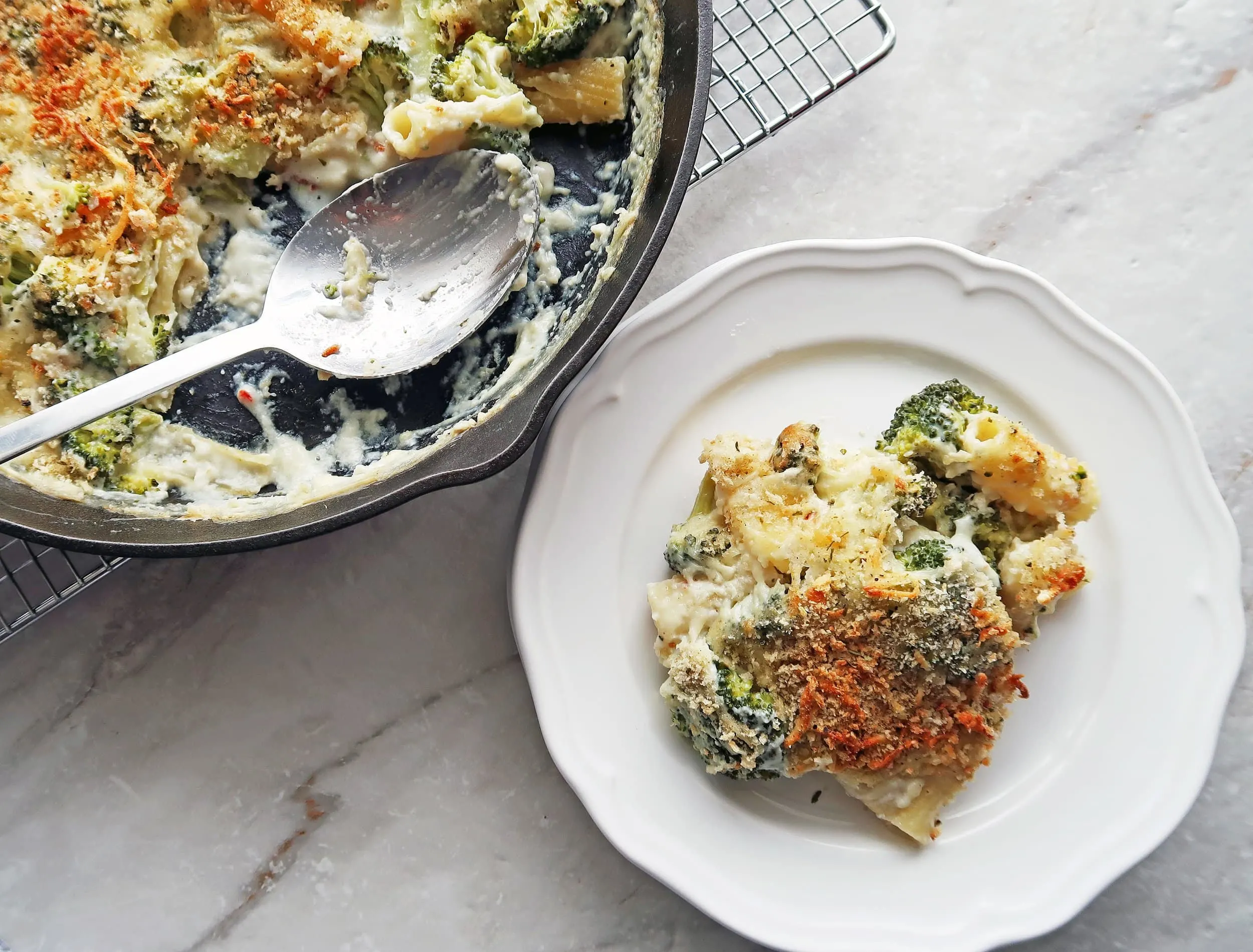 A plate of baked pasta with broccoli and white cheese sauce.