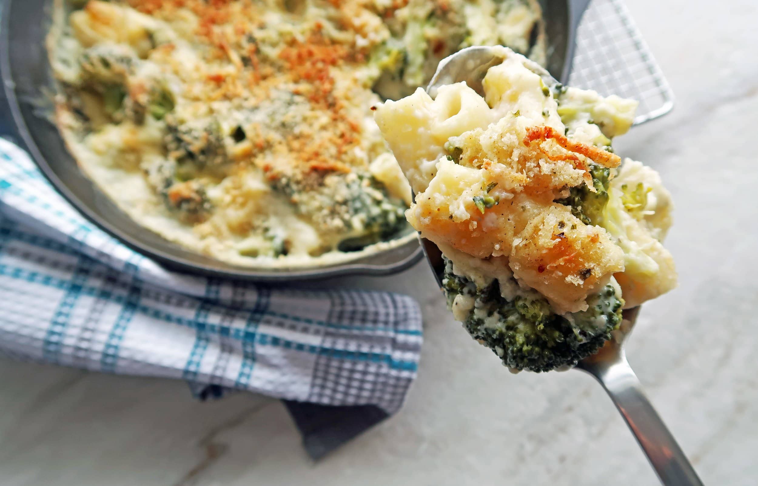A spoon full of broccoli and white cheese sauce baked pasta.