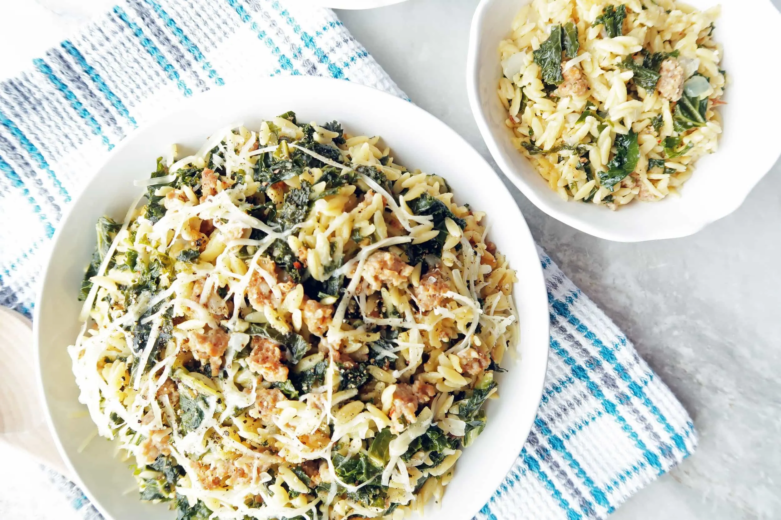 Orzo pasta with Italian sausage and kale in a large pasta bowl and in a small bowl.
