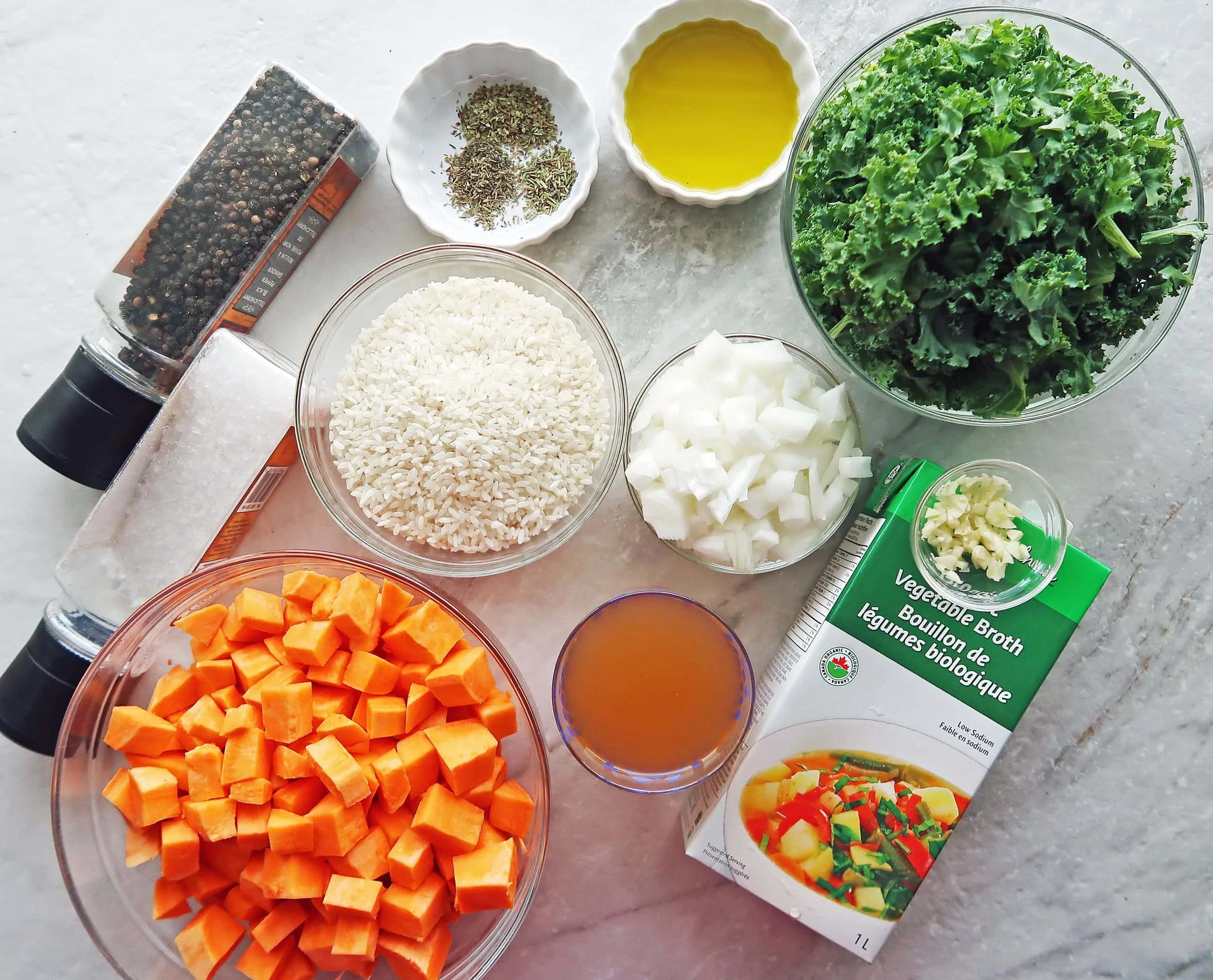 Bowls of sweet potato, onion, kale, arborio rice, vegetable broth, and herbs.