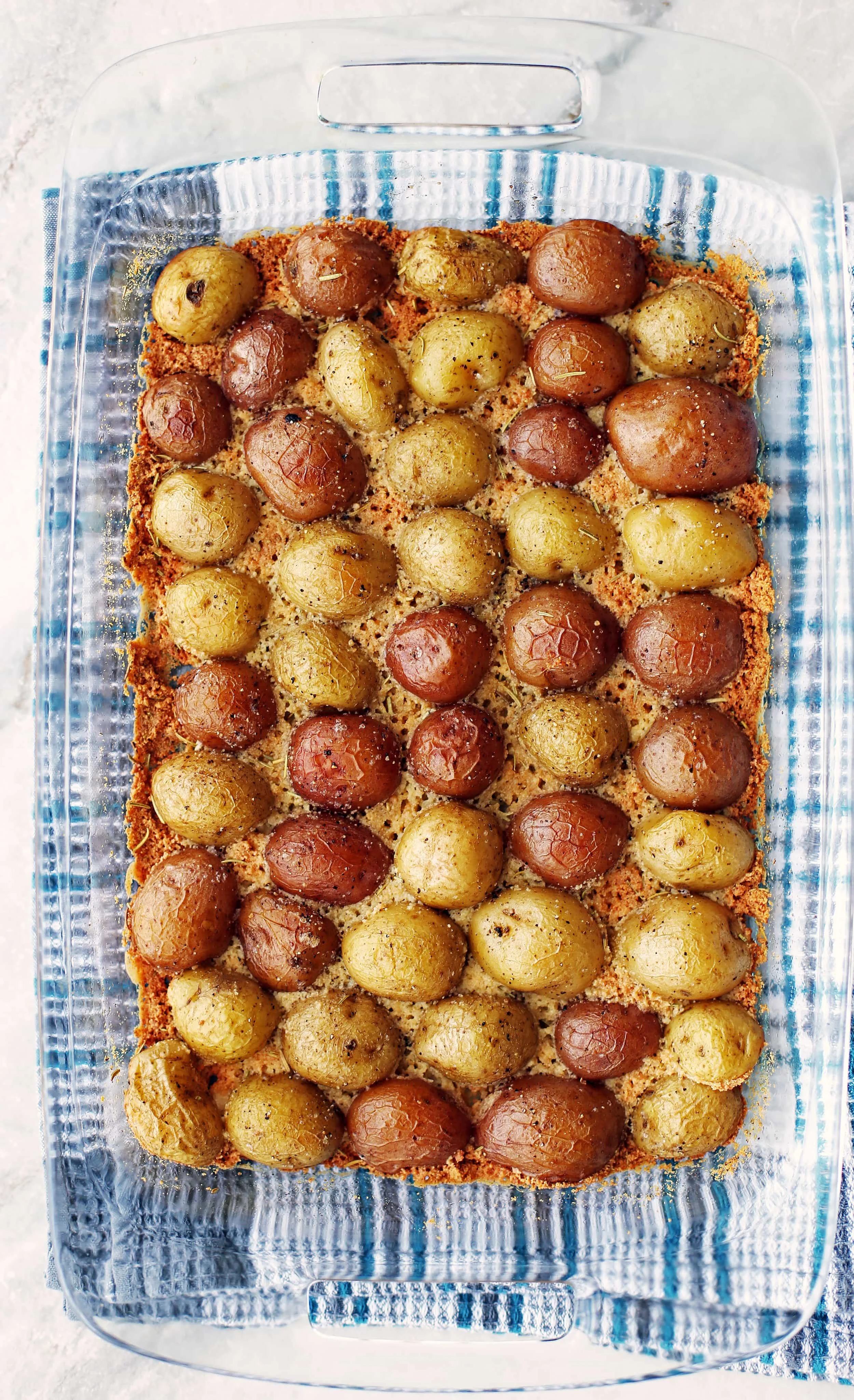 Baked Crispy Parmesan Crusted Baby Potatoes in a single layer in a glass casserole dish.