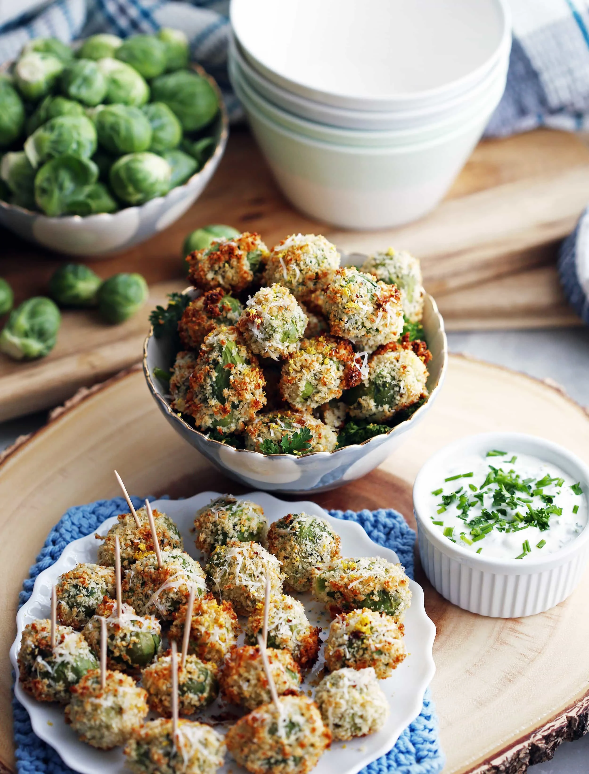 Parmesan Panko Brussels sprouts in a blue bowl and on a white plate with sour cream dip in a ramekin.