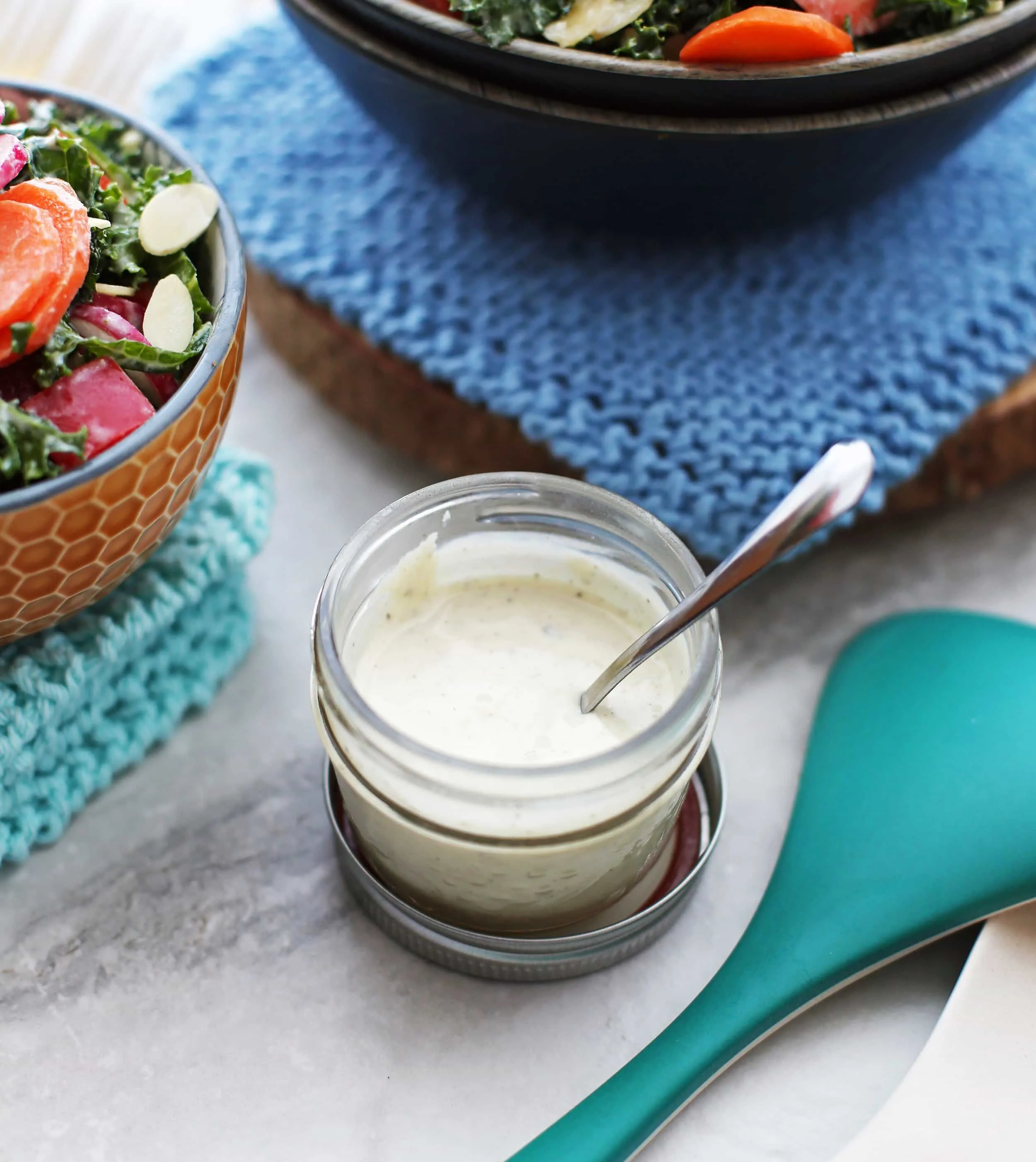 Homemade creamy parmesan yogurt dressing in a small mason jar with a little spoon in the jar.