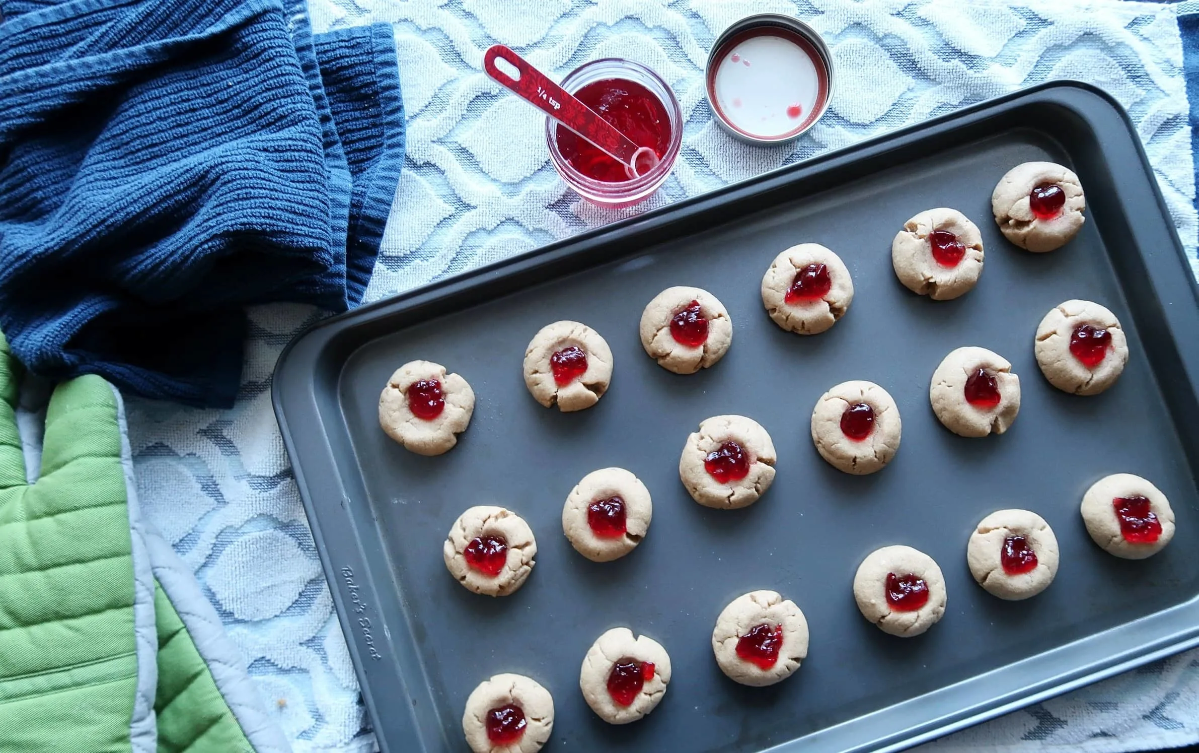 A baking sheet full of Peanut Butter and Jelly Thumbprint Cookies.