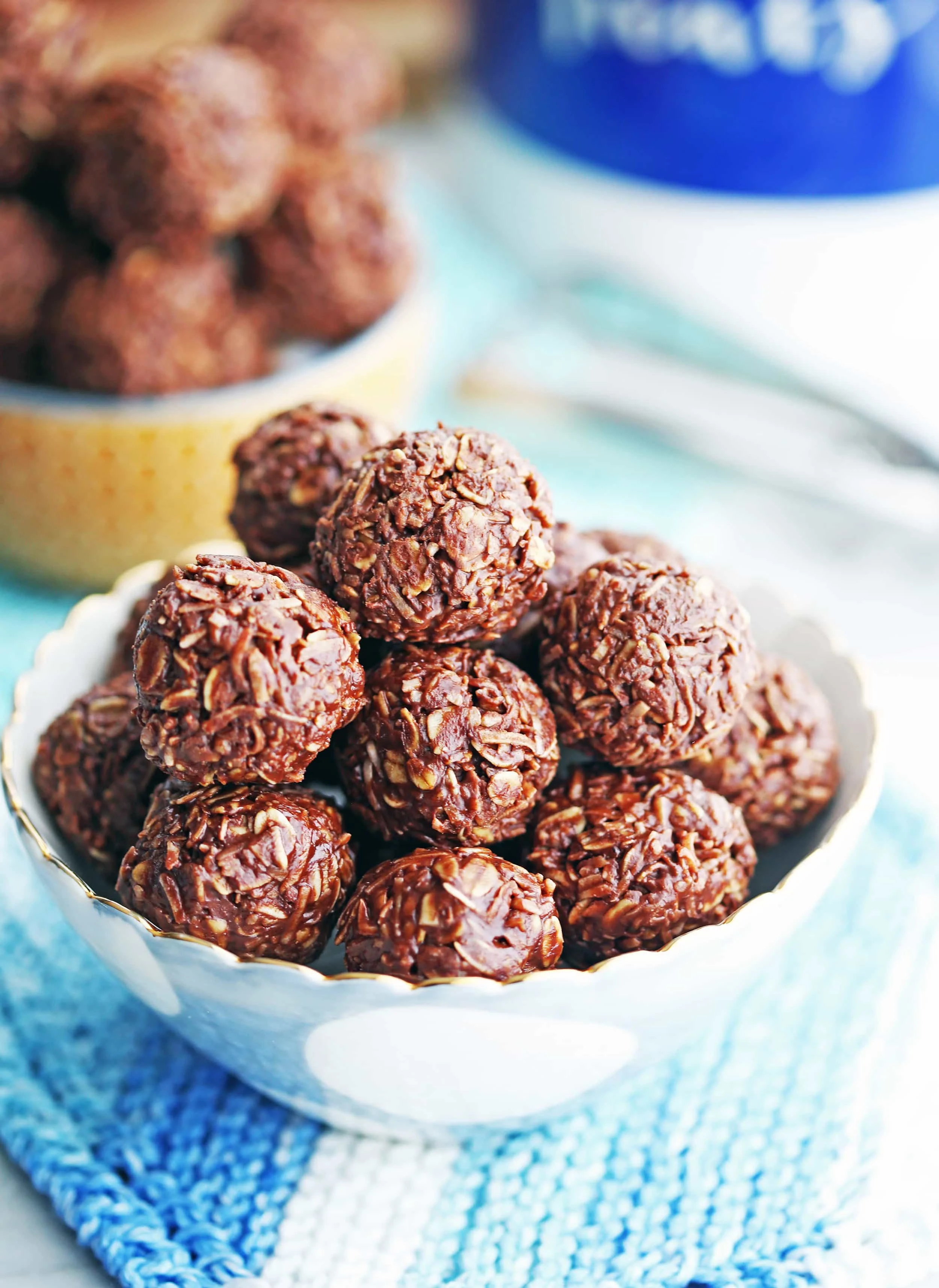 A small blue and white bowl containing mini ball-shaped No-Bake Peanut Butter Chocolate Coconut Cookies.