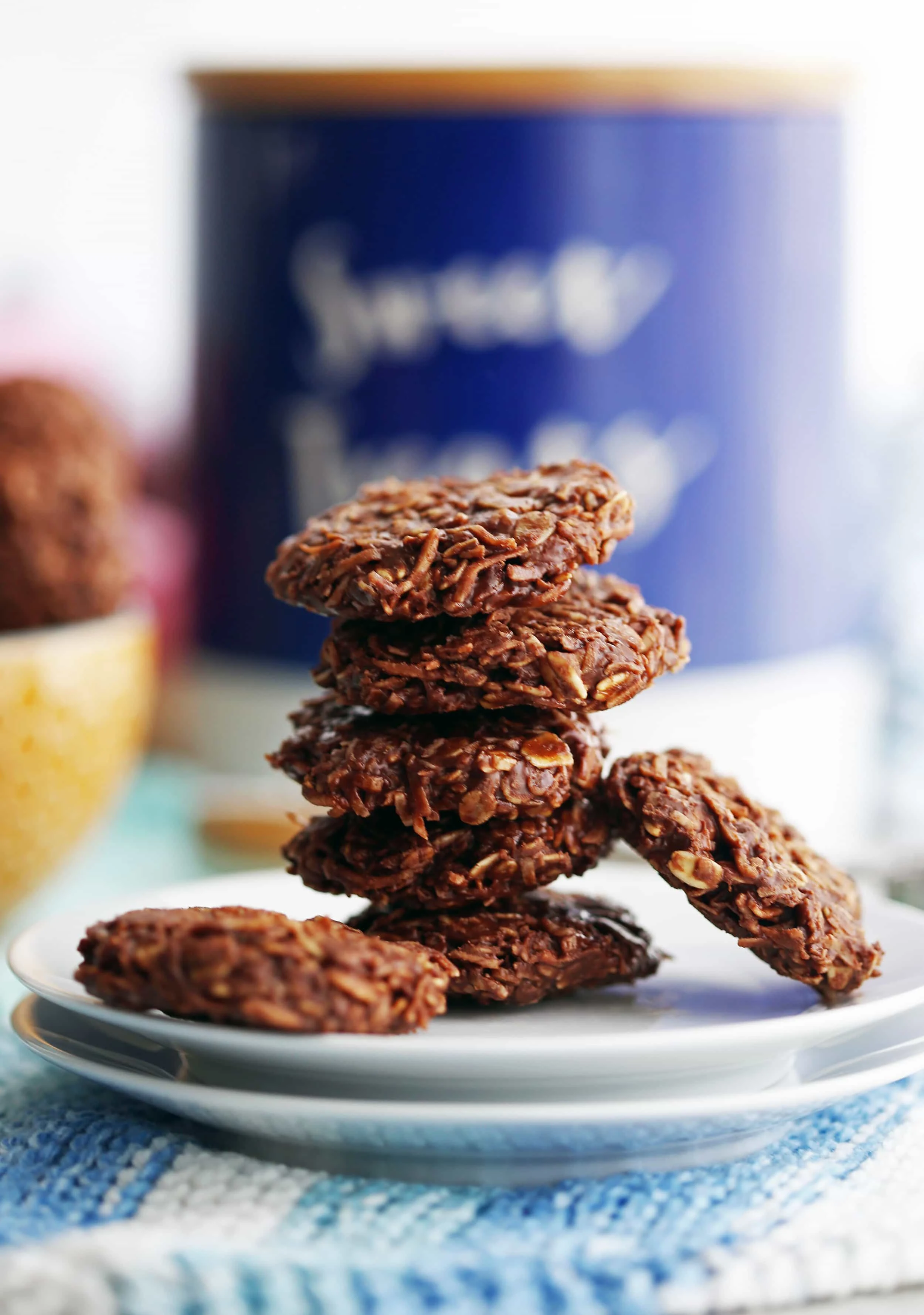 Five No-Bake Peanut Butter Chocolate Coconut Cookies stacked on a white plate.