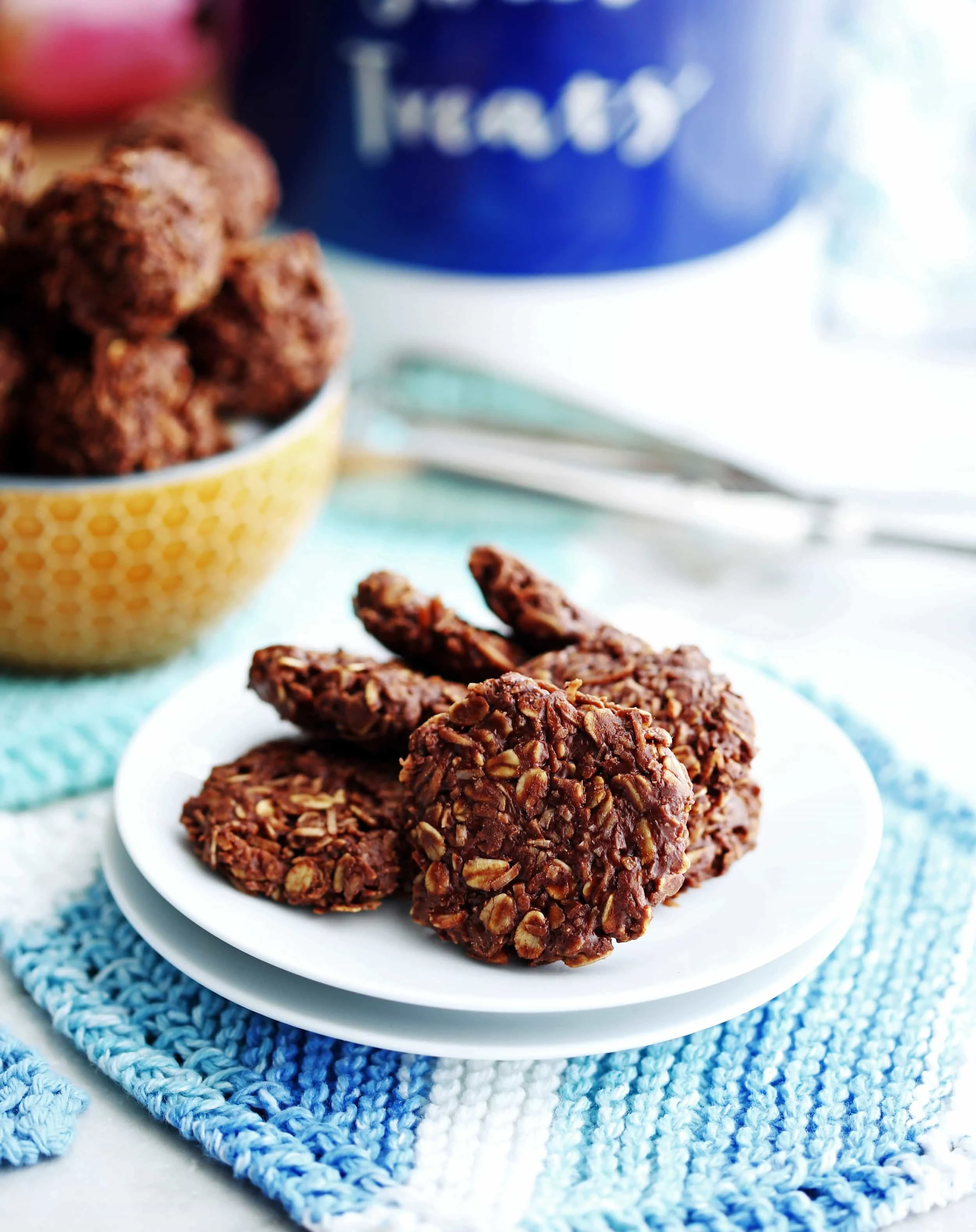 Six No-Bake Peanut Butter Chocolate Coconut Cookies overlapping one another on a small white plate.