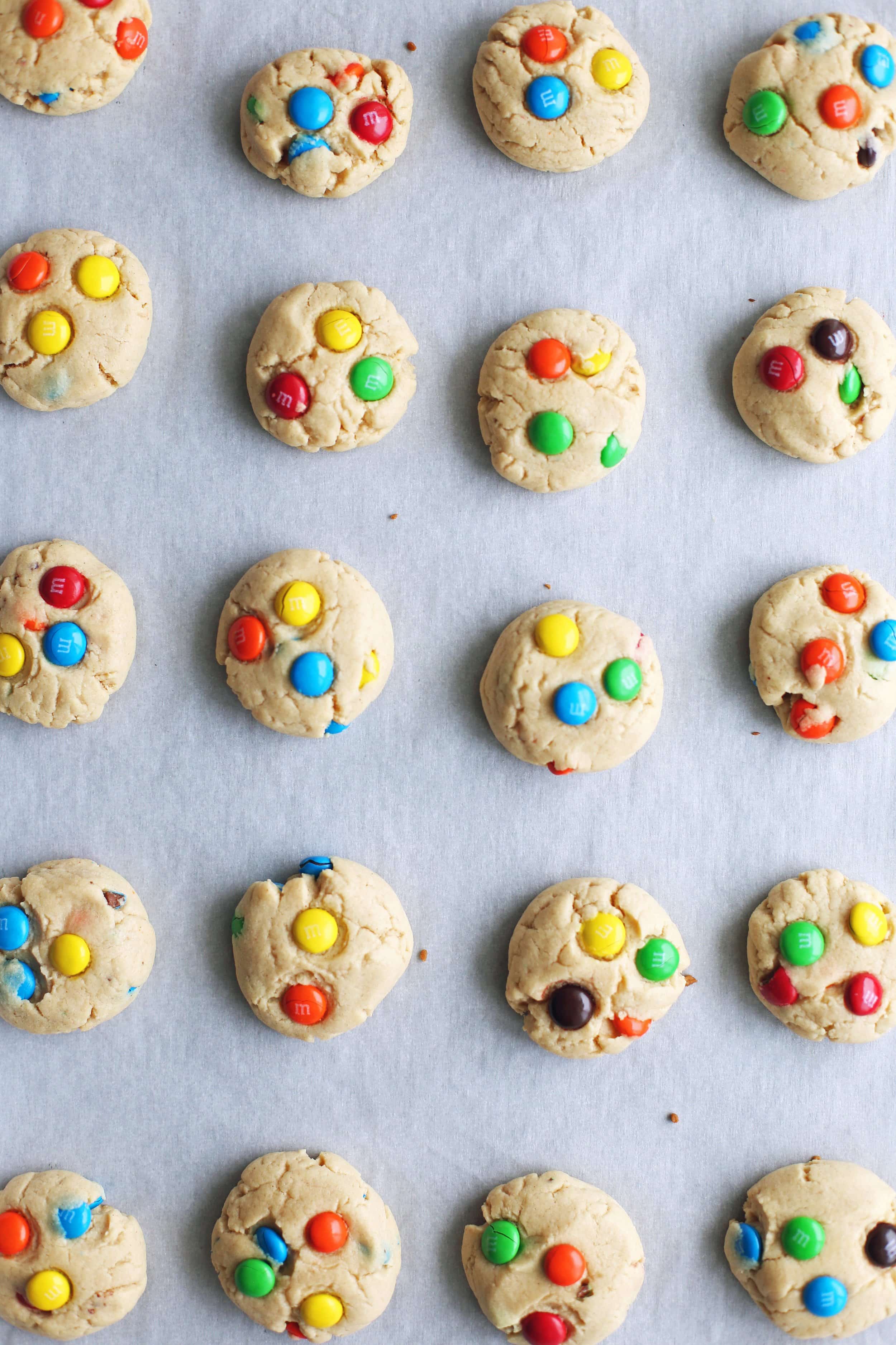 Rows of baked Chewy Peanut Butter Cookies with Chocolate M&M's on a parchment paper lined baking sheet.