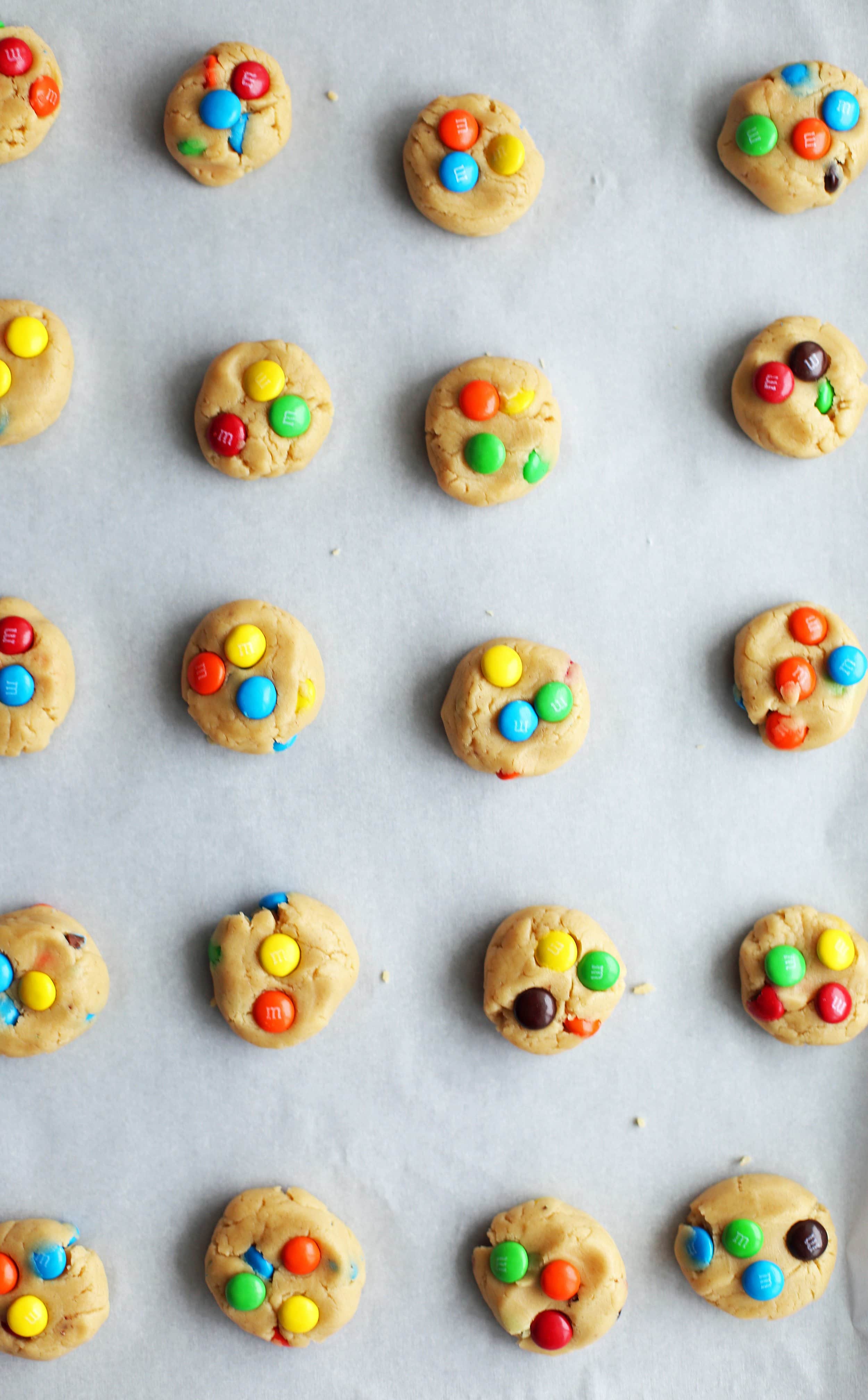 Cookie dough shaped into flattened one inch discs with colourful M&M's pressed on top.