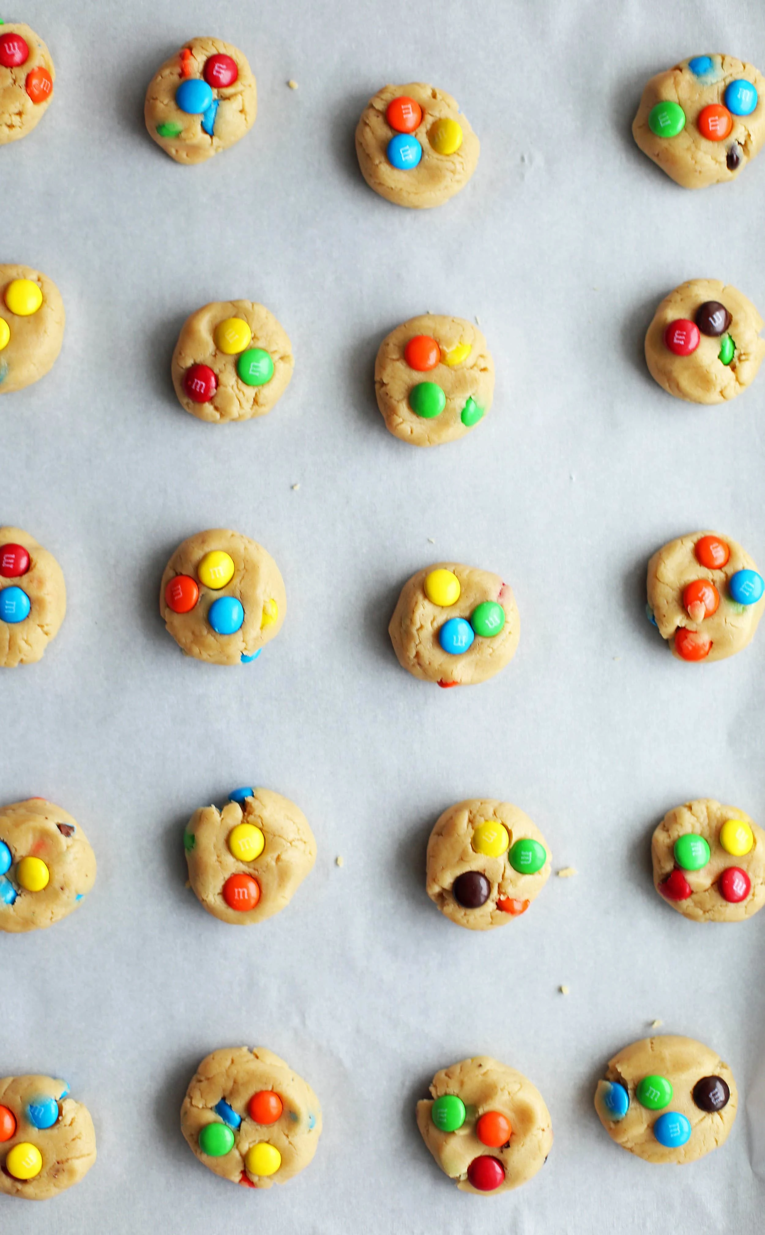 Cookie dough shaped into flattened one inch discs with colourful M&M's pressed on top.