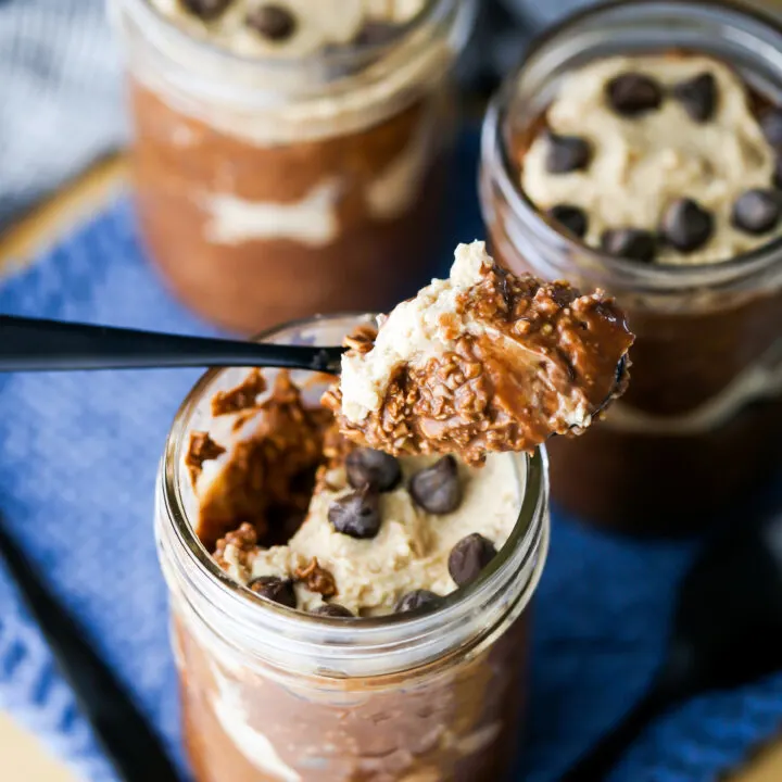 Peanut Butter Mocha Overnight Oats in three mason jars. A spoonful of oats is taken out of one.