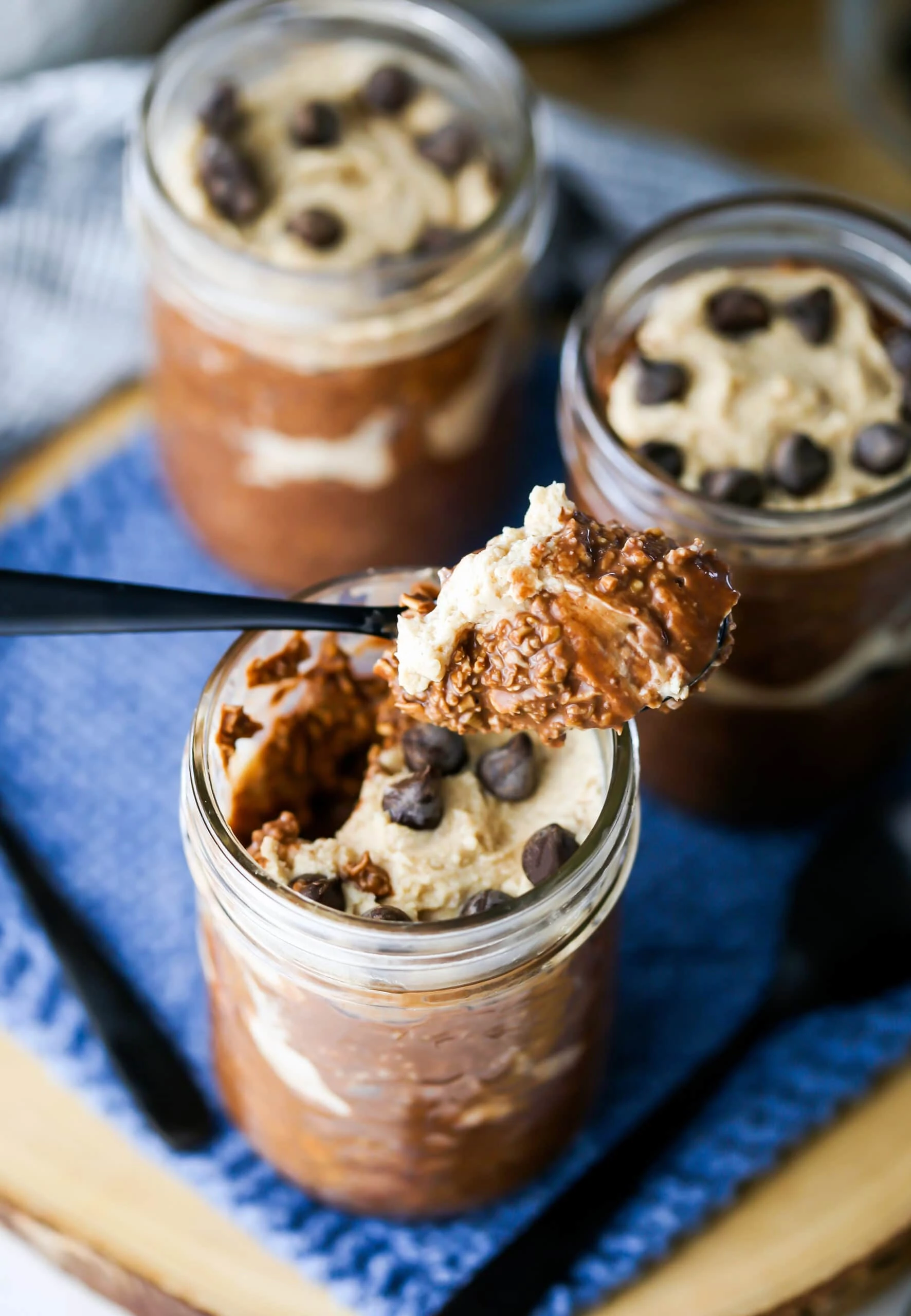 Peanut Butter Mocha Overnight Oats in three mason jars. A spoonful of oats is taken out of one.