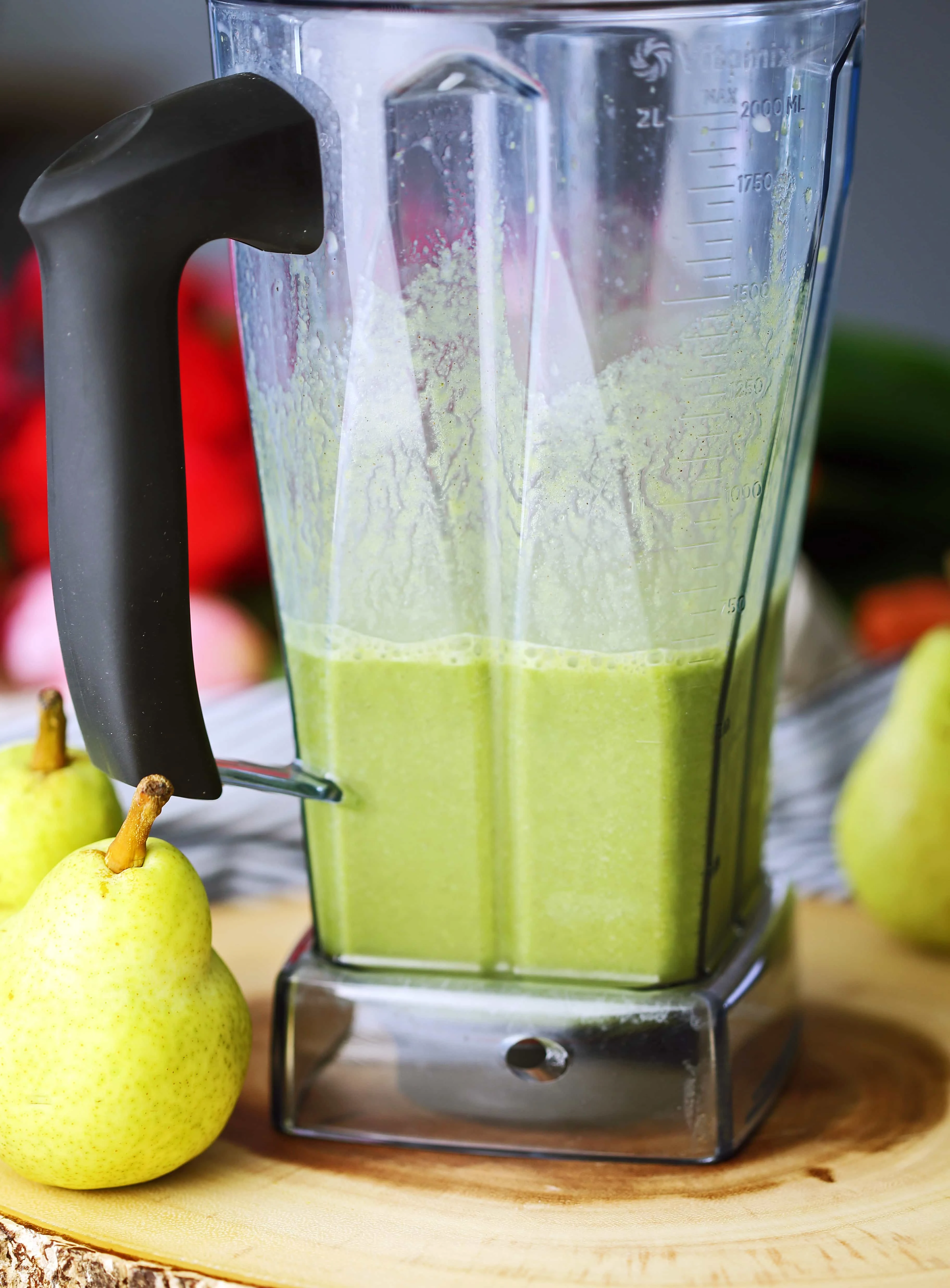 A blender container with cinnamon pear green smoothie in it.