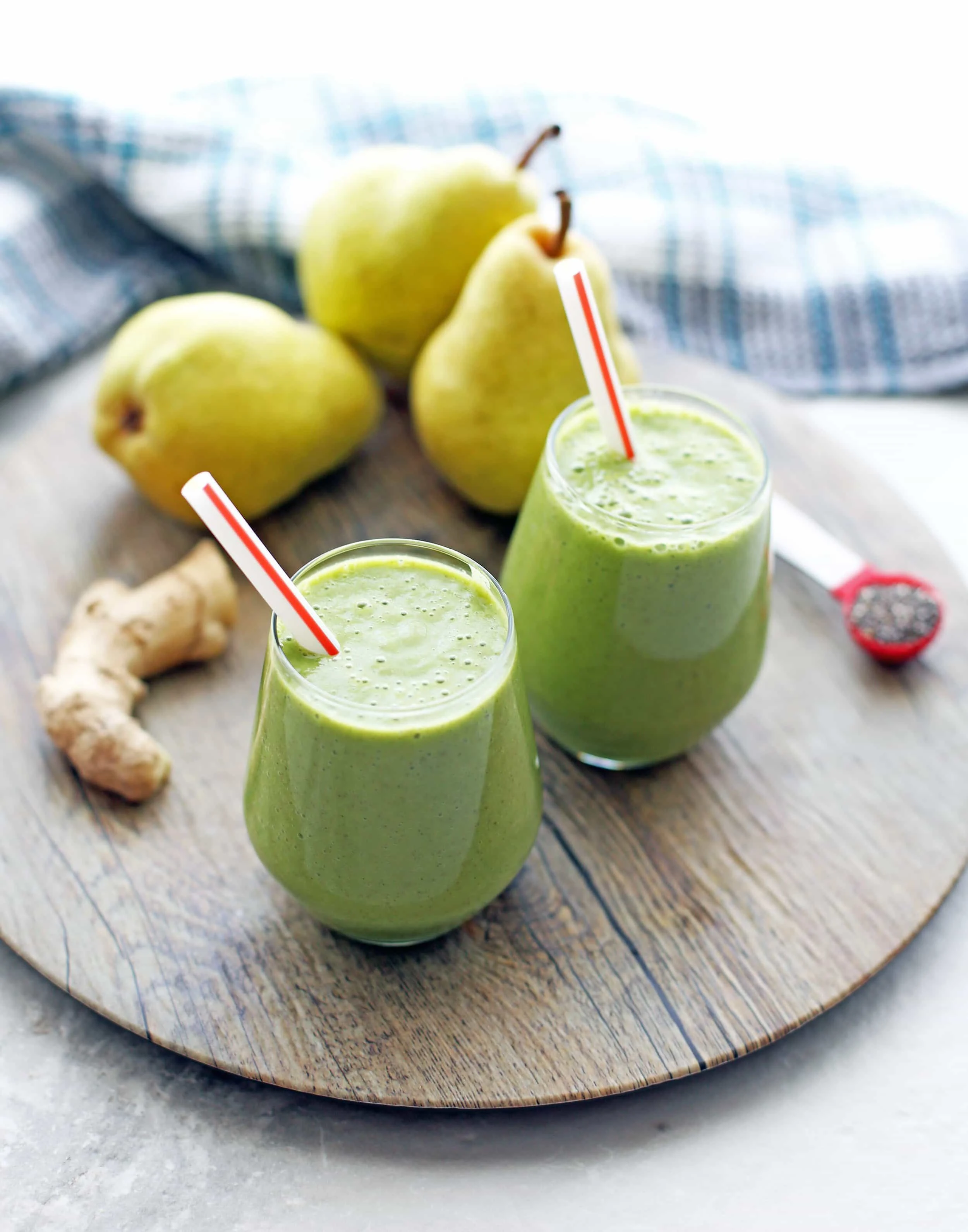 Top angled view of two glasses of pear ginger chia smoothies on a wooden platter.