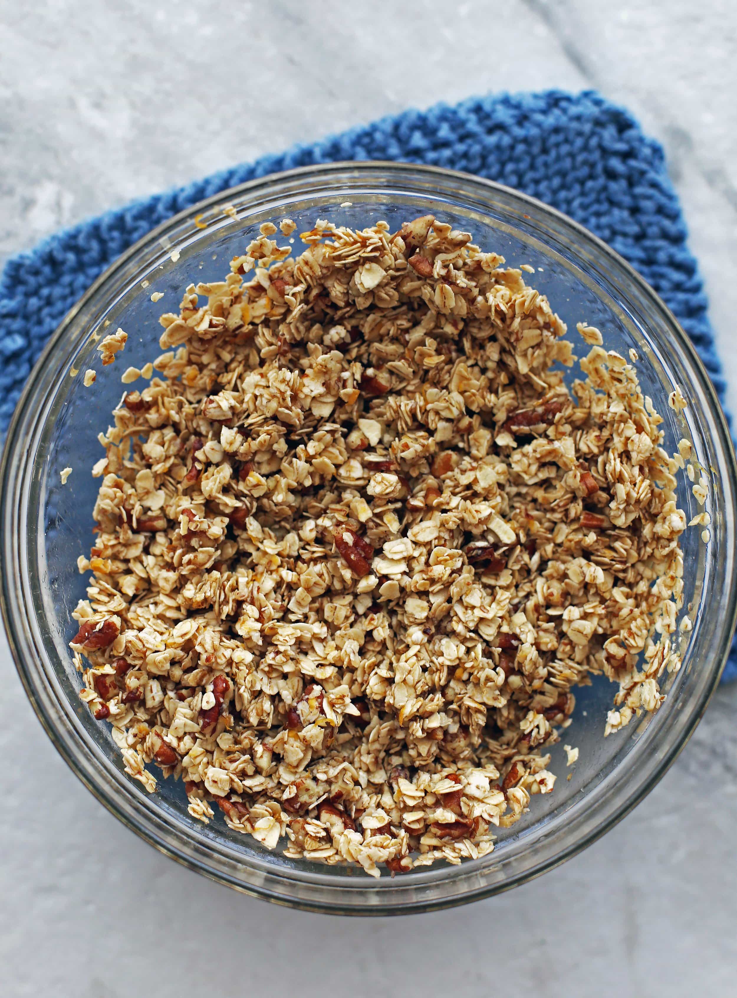 Quick oats, pecans, cinnamon, and maple mixed together in a glass bowl.