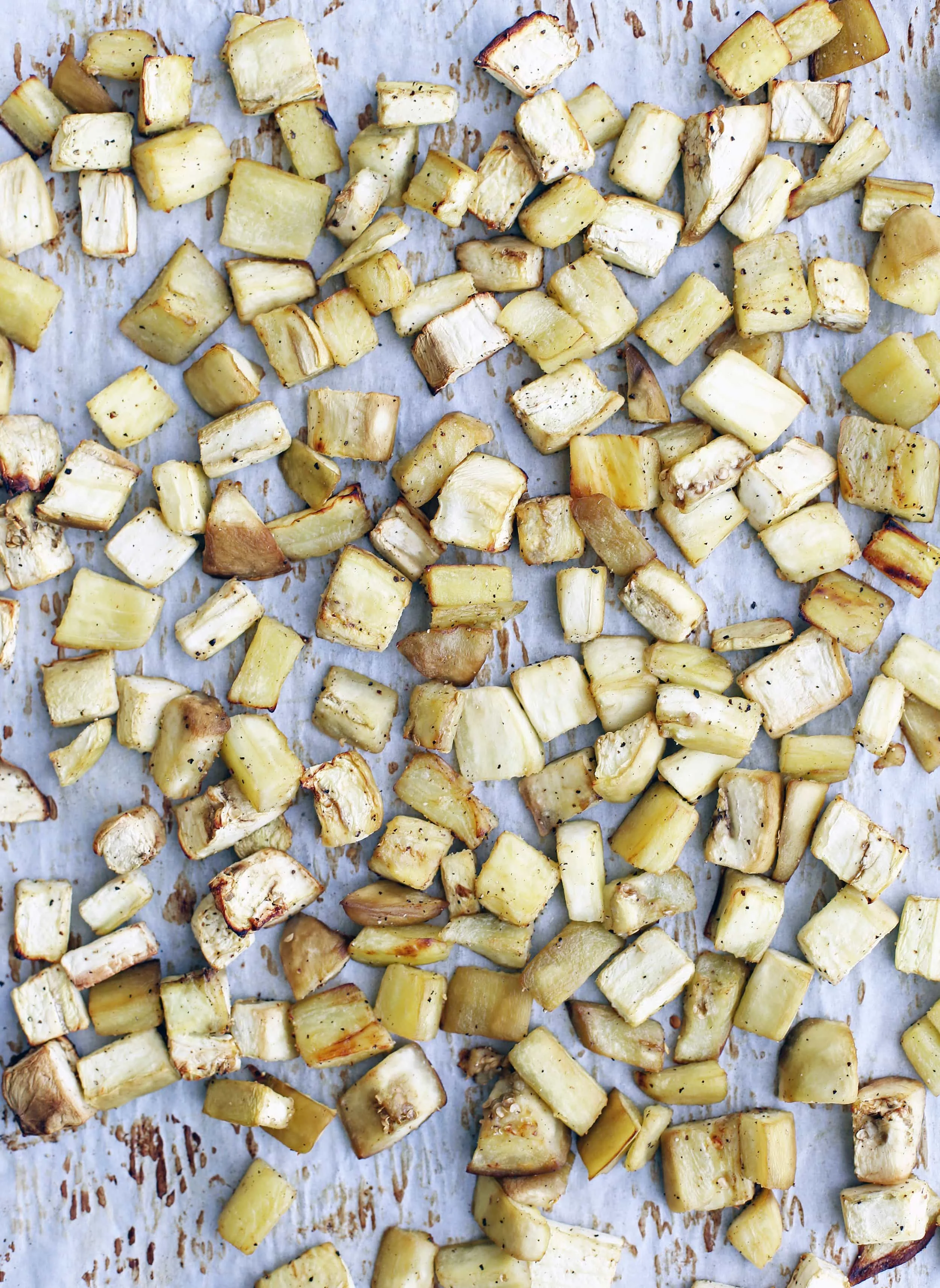 Roasted chopped Italian eggplant on a parchment paper lined baking sheet.